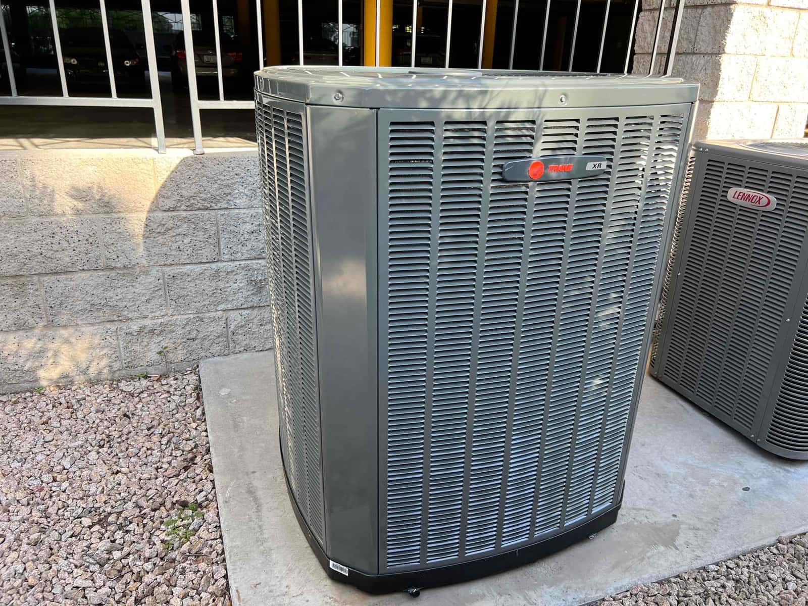 New outdoor condenser set on a level pad with proper clearance beside another unit at the installation site.