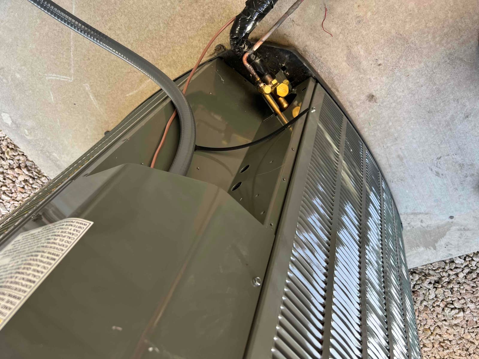 New outdoor condenser set on a pad with insulated refrigerant lines connected and service valves accessible for commissioning.
