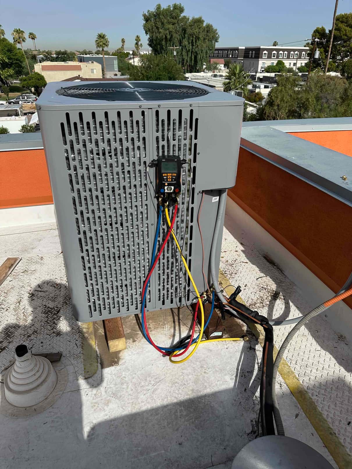 New rooftop heat pump condenser with digital manifold gauges connected to service ports and insulated line set routed to the unit.