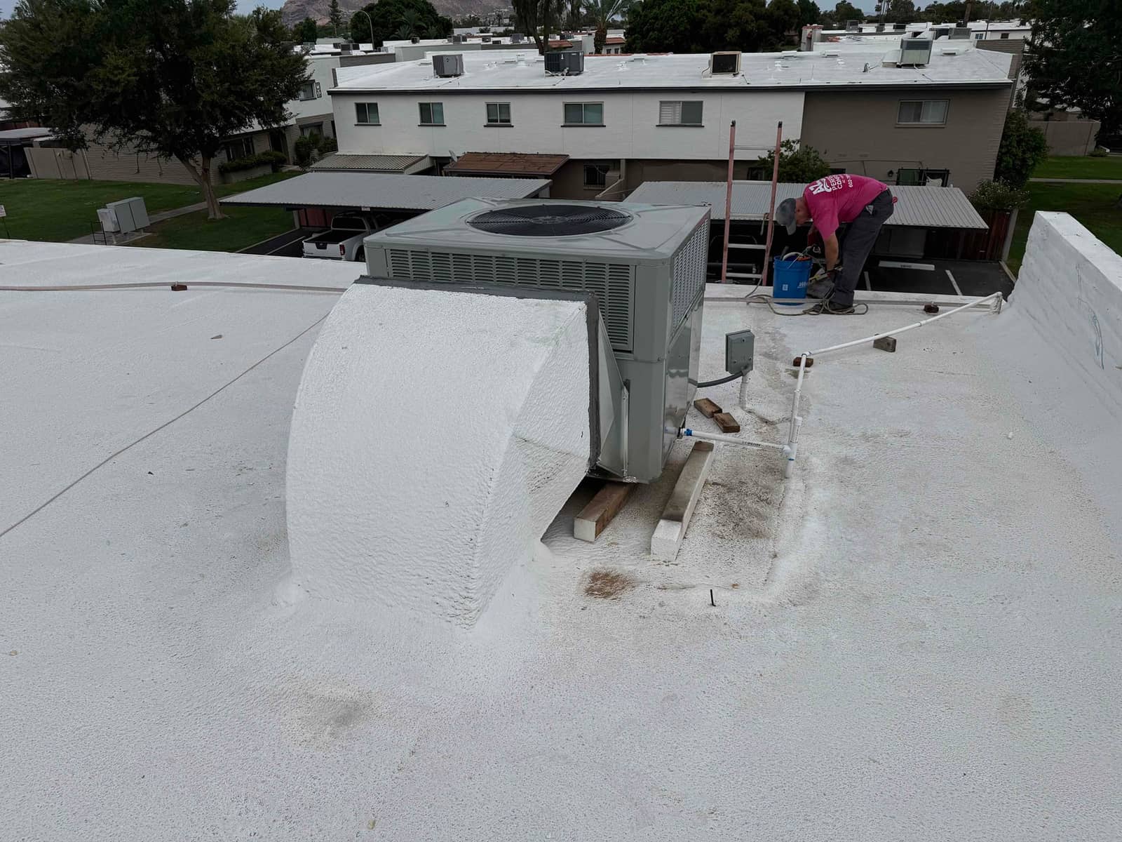 New rooftop package unit set on curb with connected electrical whip and condensate drain, technician organizing tools beside the installation.