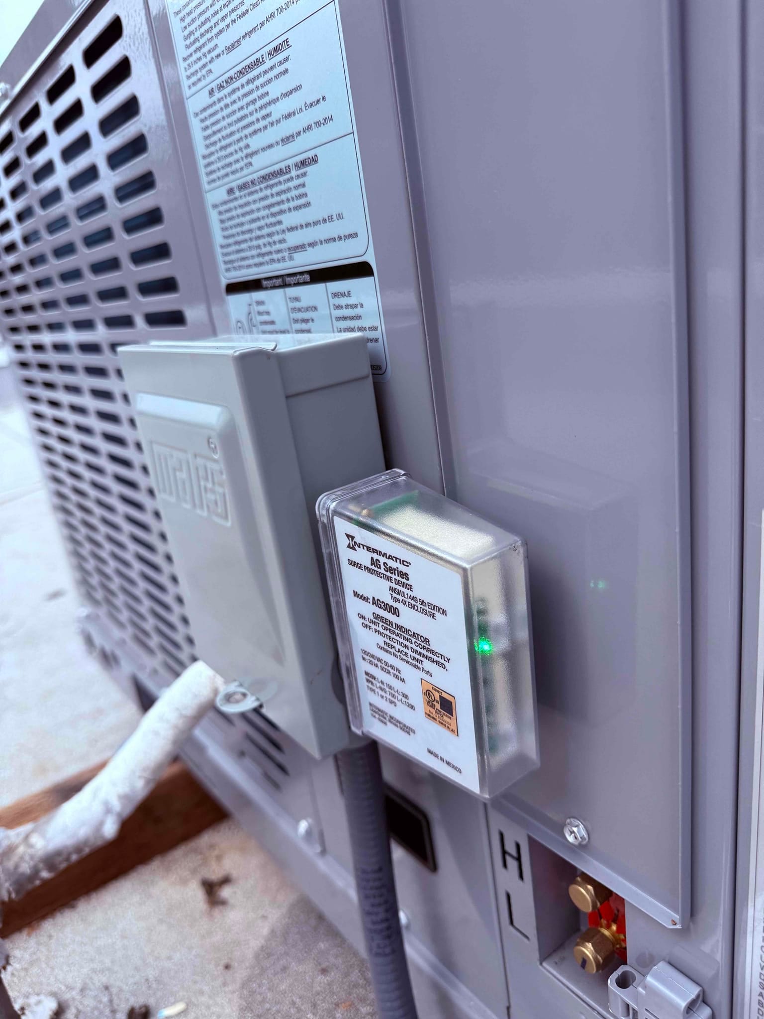 Outdoor package unit with installed disconnect, surge protector showing green indicator, insulated line set, and service ports accessible.