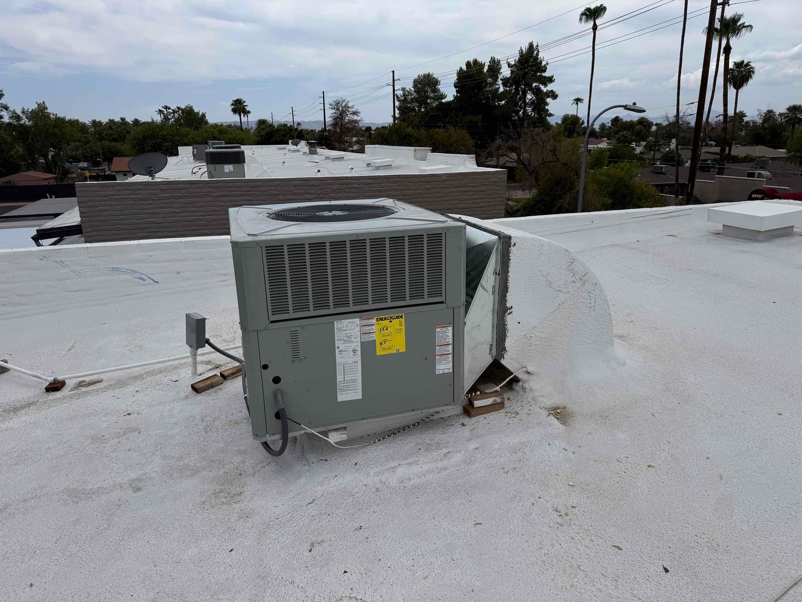 Rooftop packaged HVAC unit set on a coated flat roof with sealed curb connection and electrical disconnect nearby.