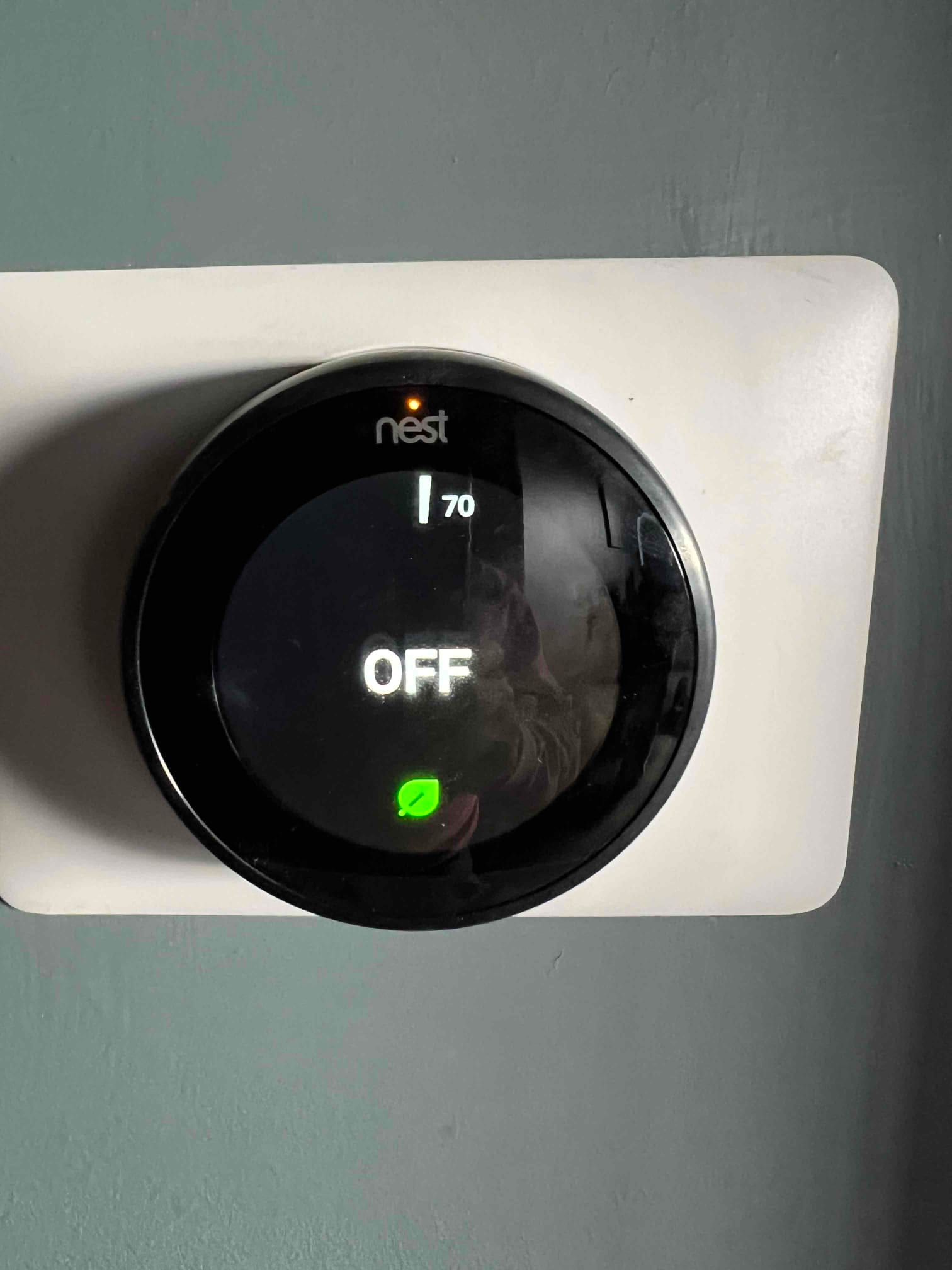 Wall-mounted smart thermostat displays OFF with a setpoint of 70 degrees after installation on a clean backing plate.