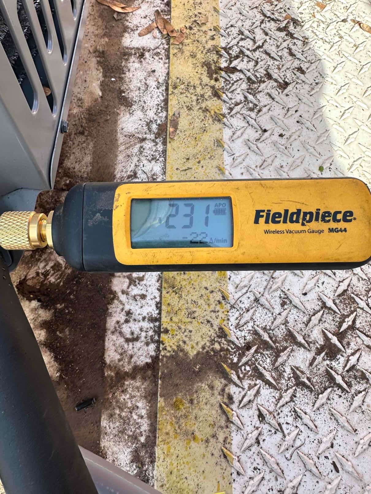 Wireless vacuum gauge connected to the system reads 231 microns, confirming a deep evacuation before releasing refrigerant.