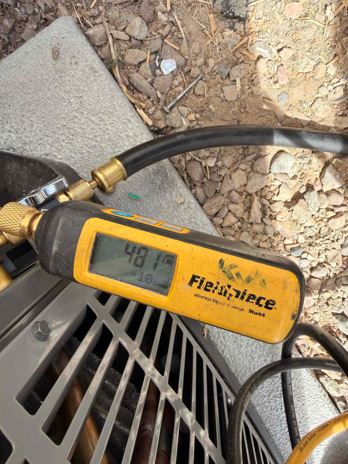 Micron gauge connected at the outdoor unit reads 487 microns, confirming a deep vacuum before releasing refrigerant.