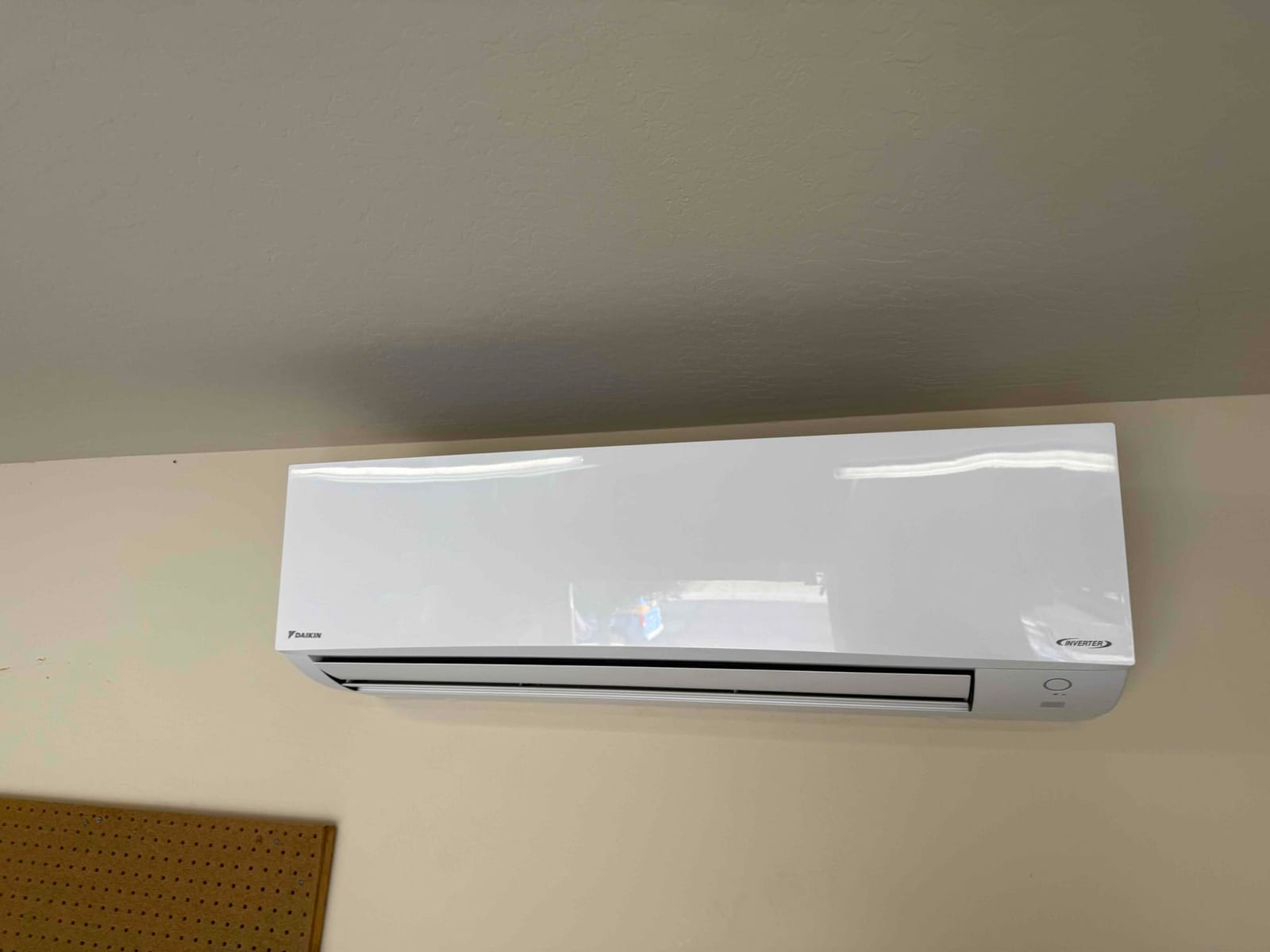 Wall-mounted mini-split indoor unit installed level on the interior wall, with discharge louvers aligned and cover closed.