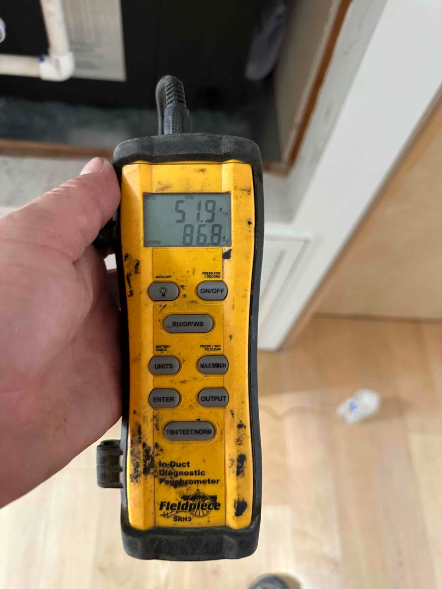 Digital thermometer shows 51.9°F supply air temperature during cooling check at the air handler.
