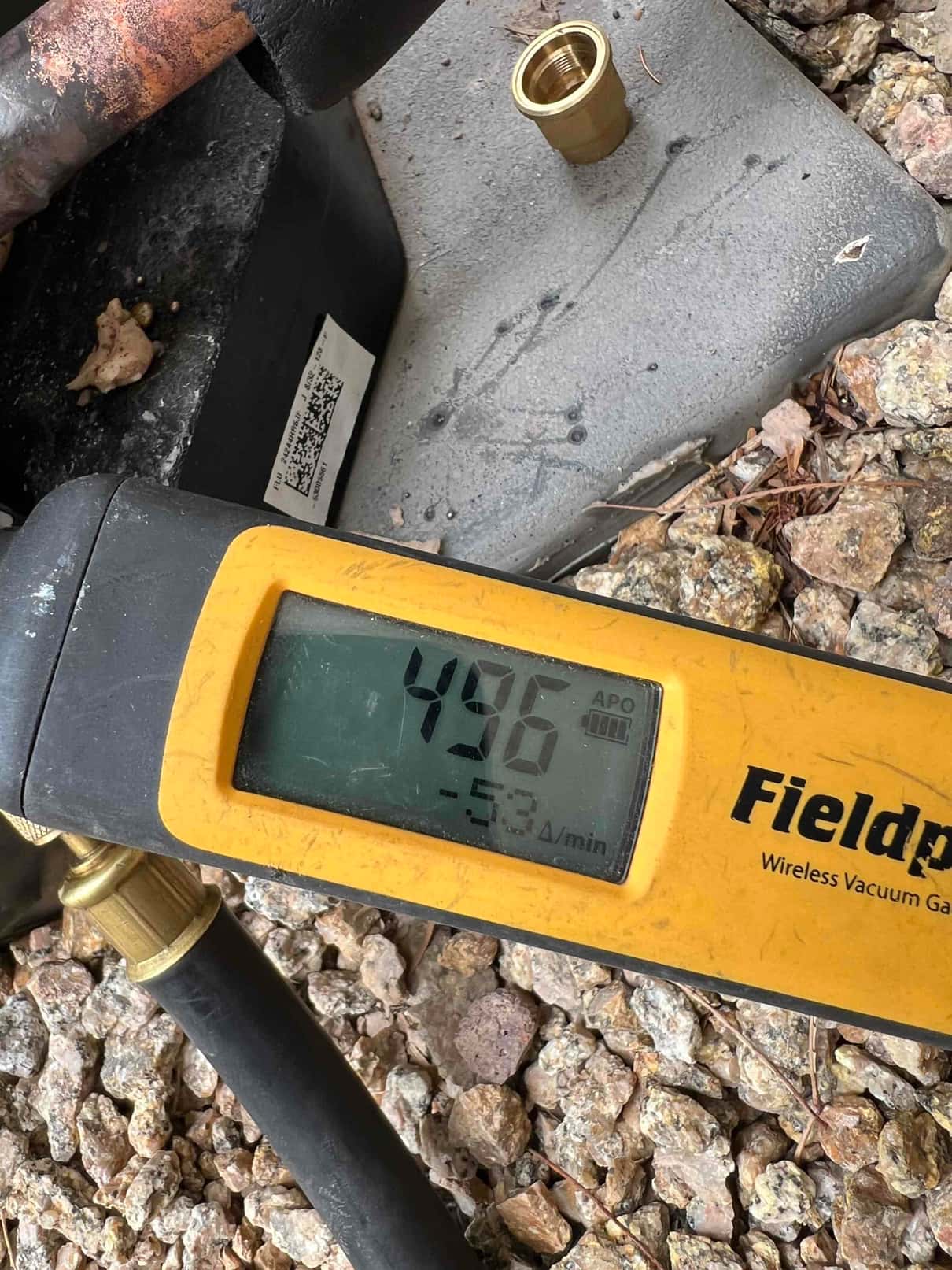Digital vacuum gauge shows 496 microns during system evacuation, confirming a deep vacuum prior to refrigerant charging.