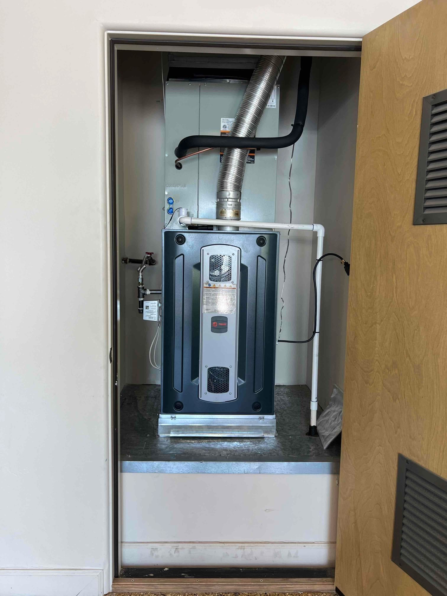 New gas furnace and evaporator coil installed in a closet, with insulated refrigerant lines, condensate drain piping, and venting connected.