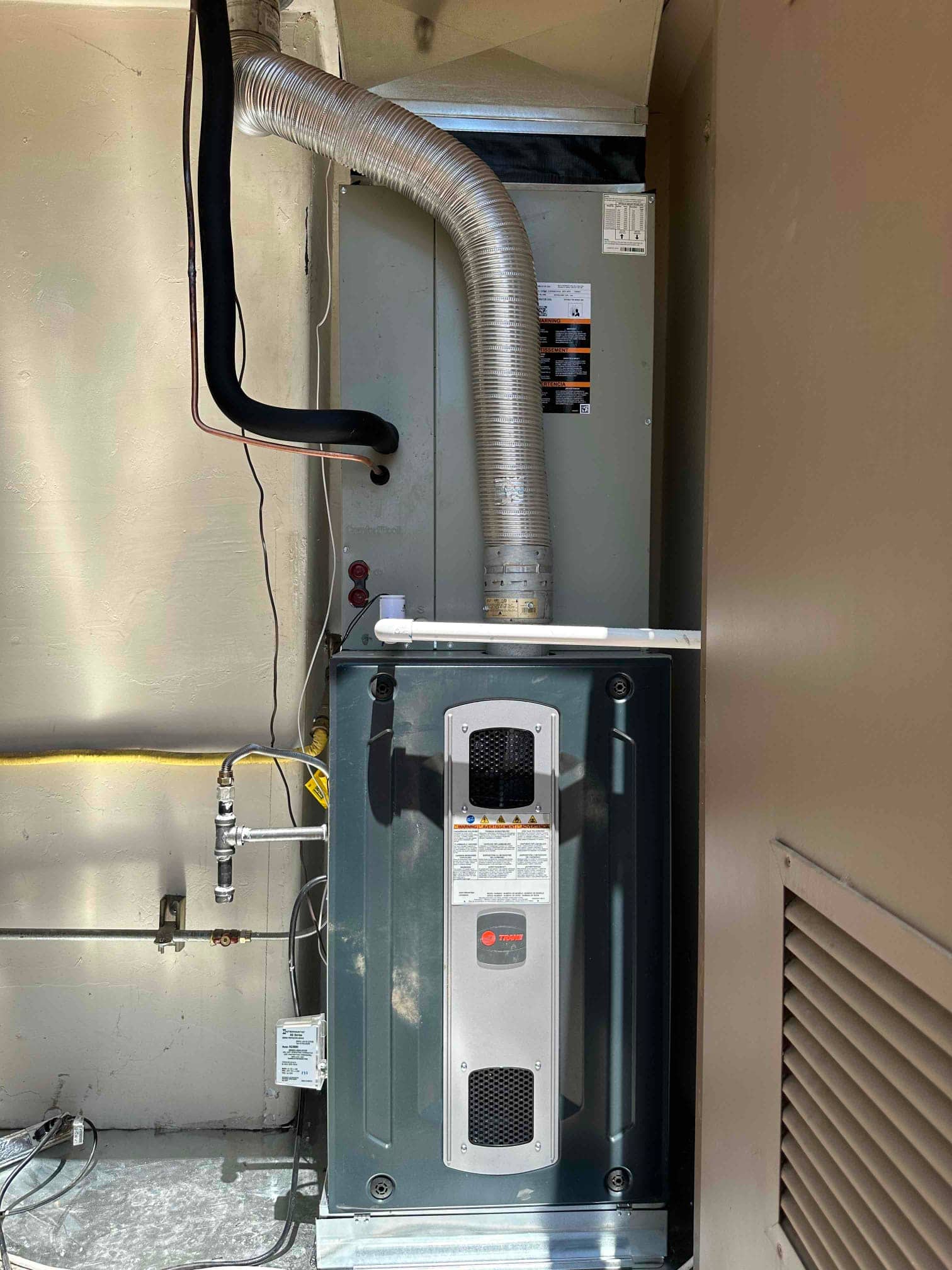 New gas furnace installed beneath an indoor coil cabinet with insulated refrigerant lines, flexible vent, gas shutoff, and condensate drain routing.