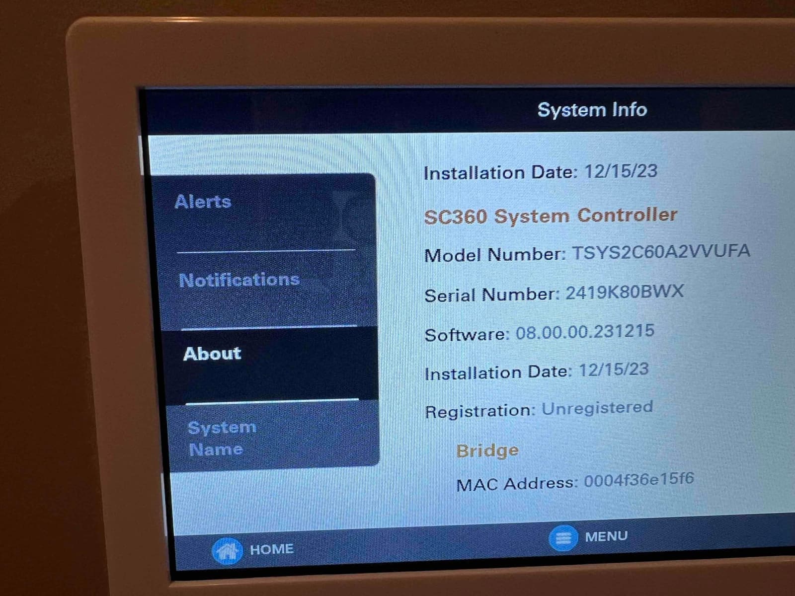 Thermostat-style system controller screen displaying system info, including model, serial, software version, installation date, and registration status.