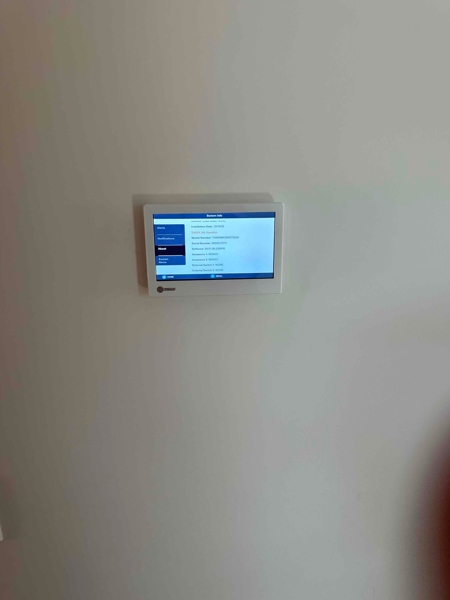 Wall-mounted touchscreen thermostat displaying system information menu after installation and setup is complete.
