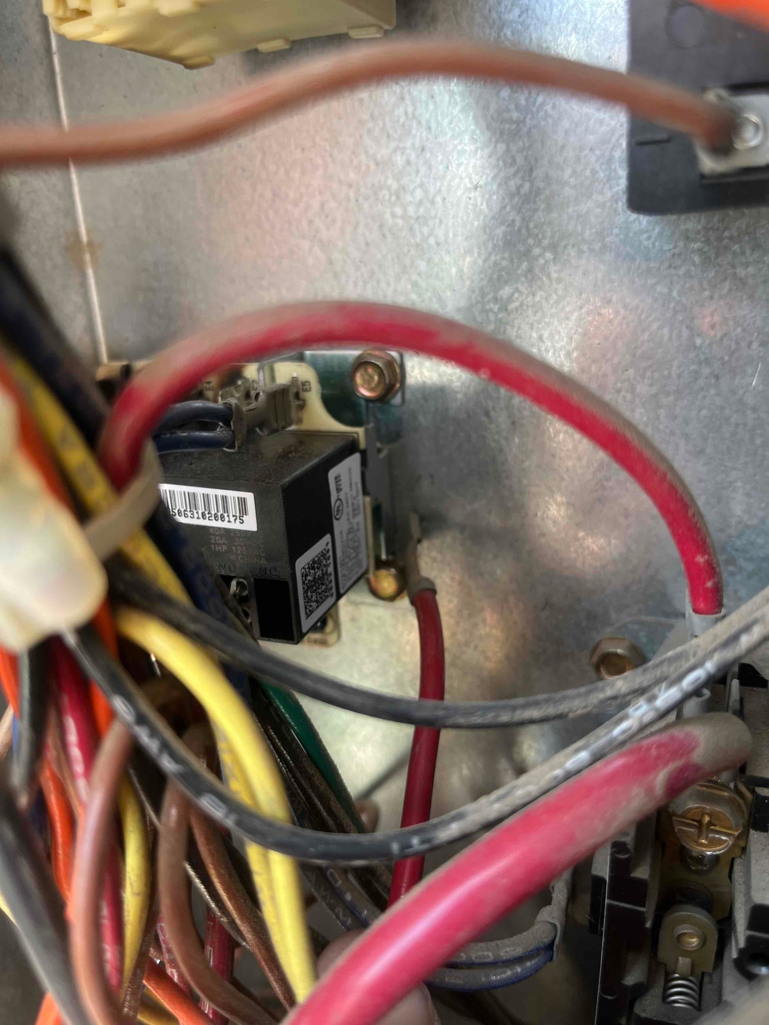 Air conditioner control compartment shows time delay relay and connected wiring harness inside the condenser unit.