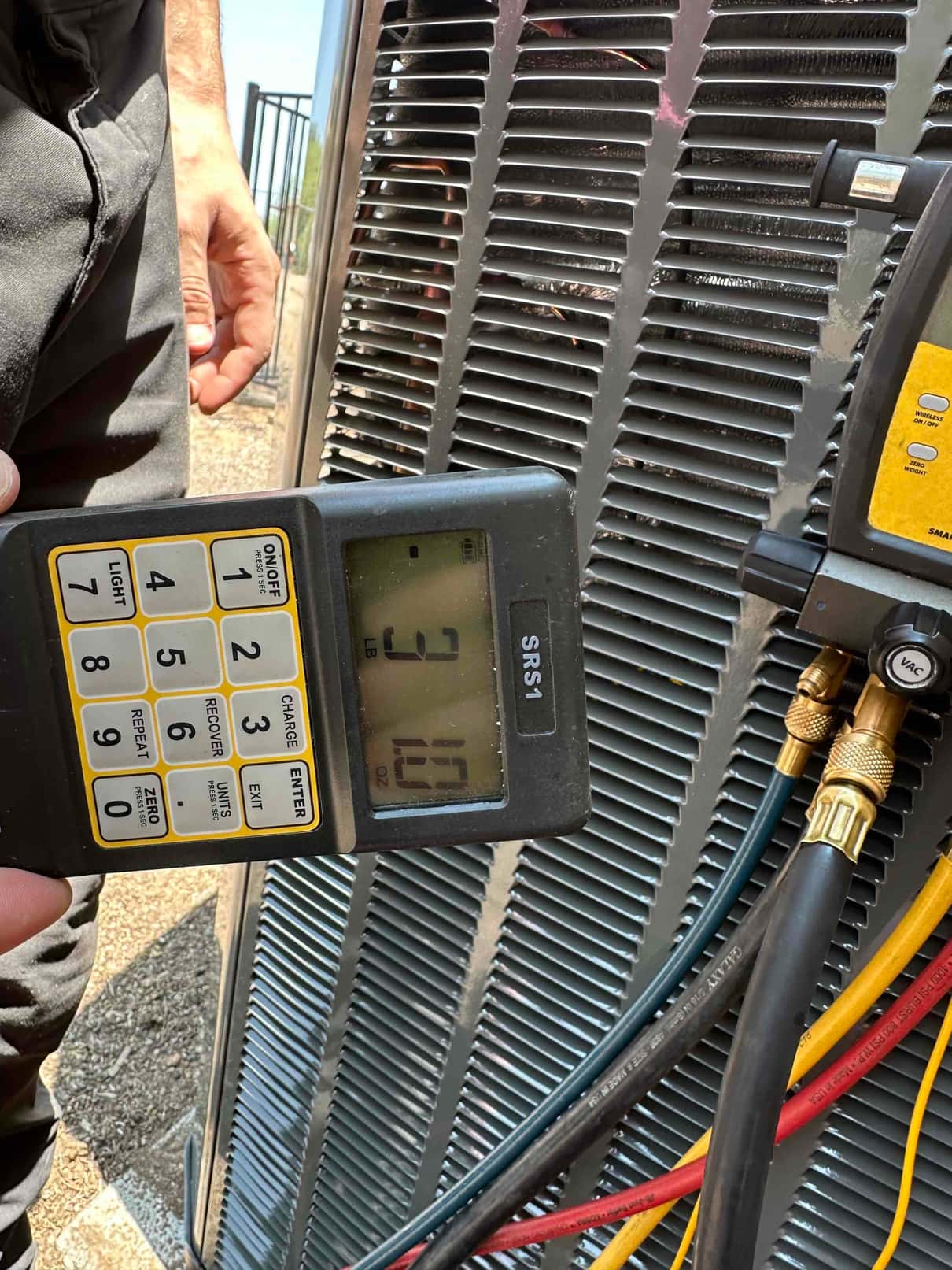 Charging scale controller and manifold hoses at the outdoor condenser during system installation work.