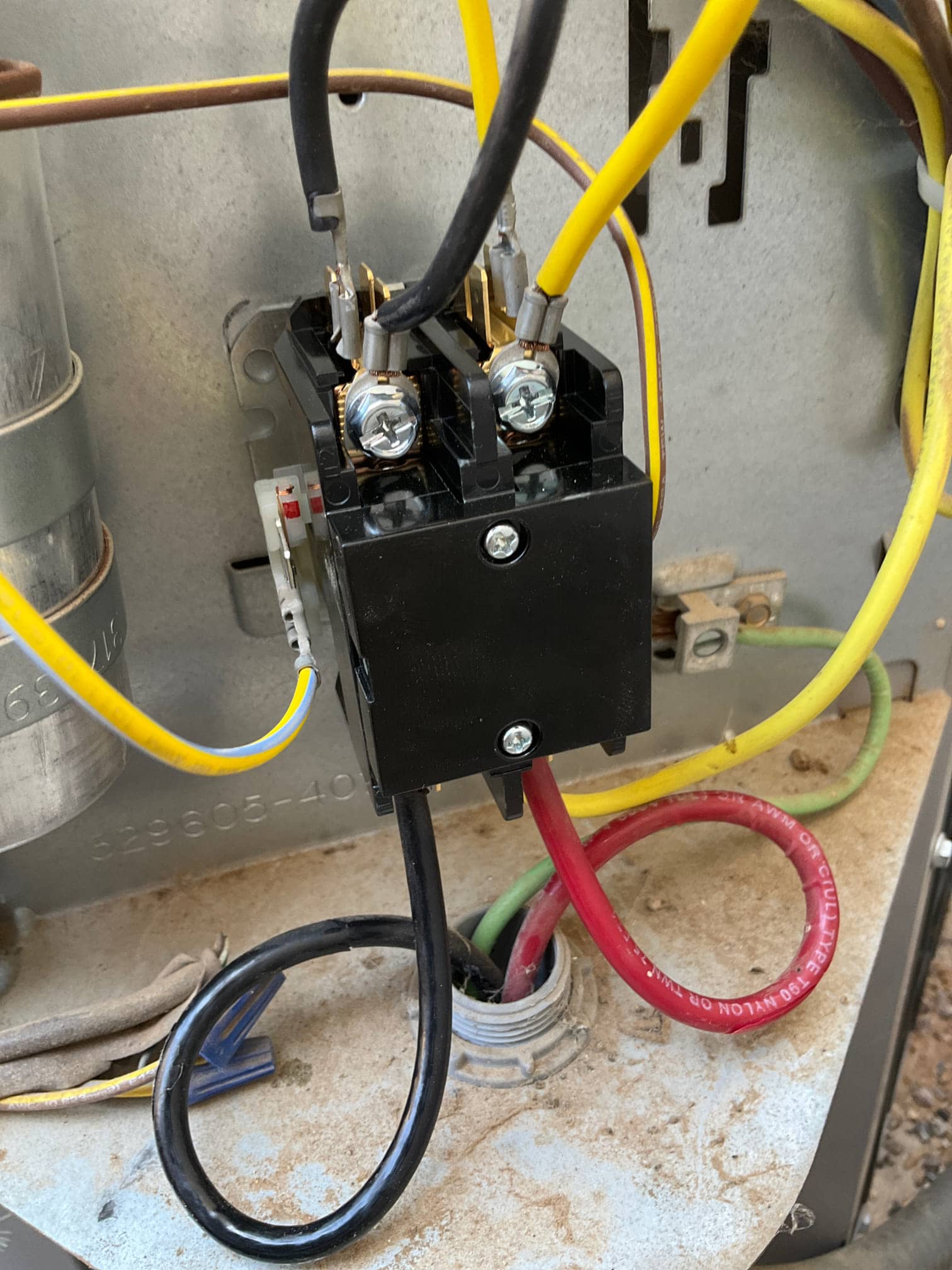 Condenser contactor with yellow control leads the customer black line conductors, red the customer green wires entering conduit, adjacent metal run capacitor.
