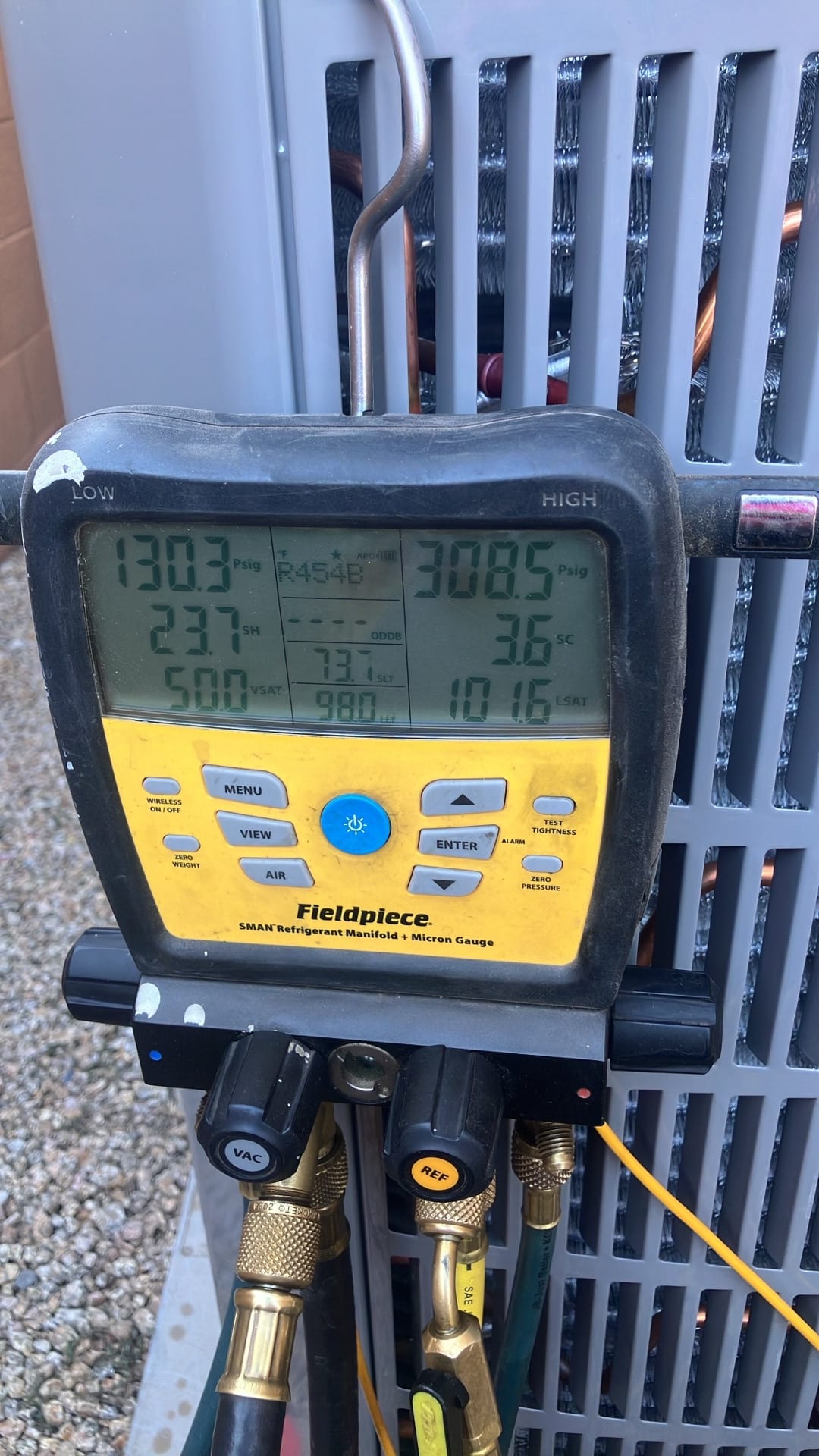 Digital manifold attached to the outdoor unit shows operating pressures and temperatures during system commissioning.