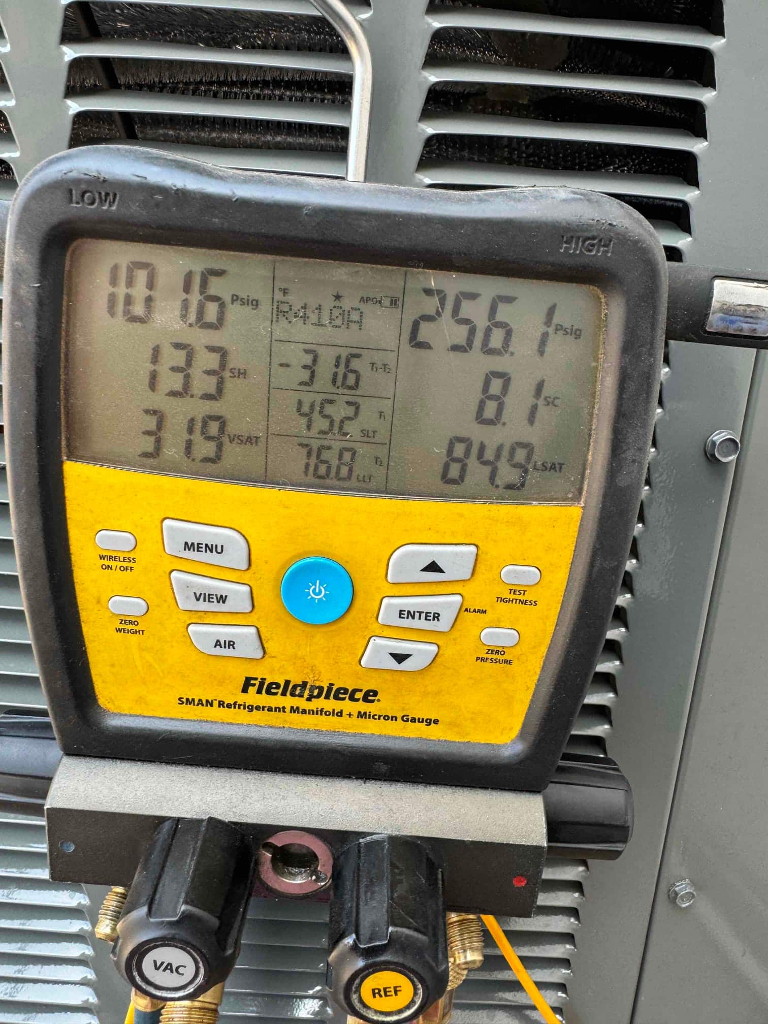 Digital manifold connected at the outdoor unit shows operating pressures and temperatures during refrigerant commissioning.