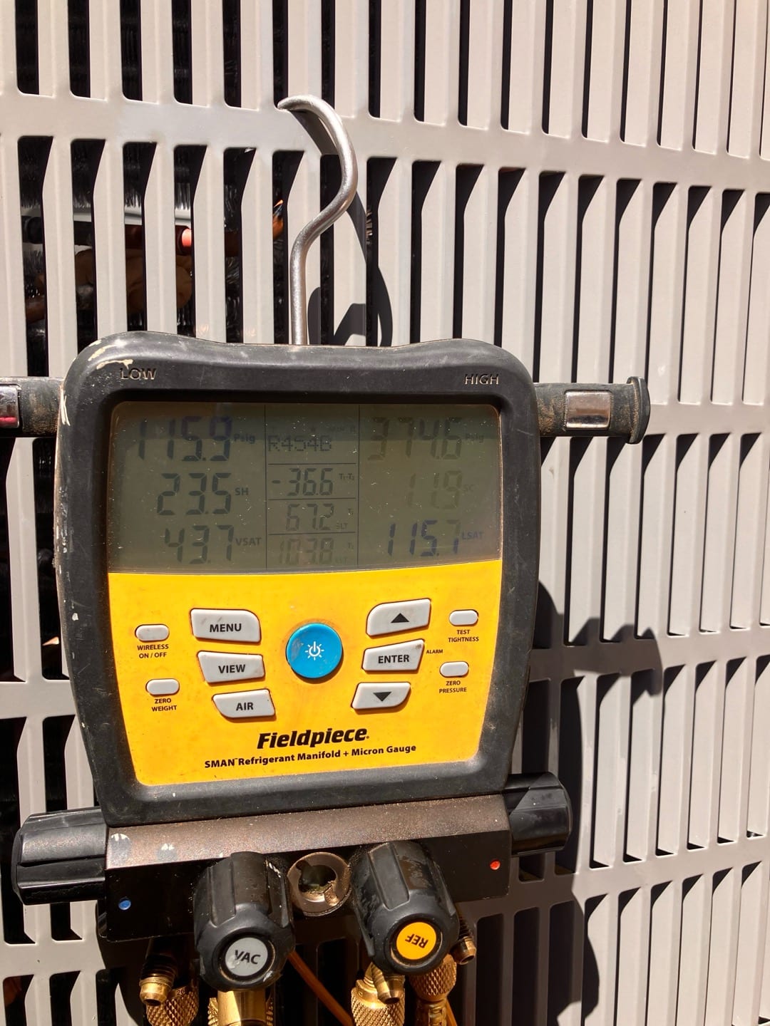 Digital manifold connected at the outdoor unit shows operating refrigerant pressures during commissioning of the new system.