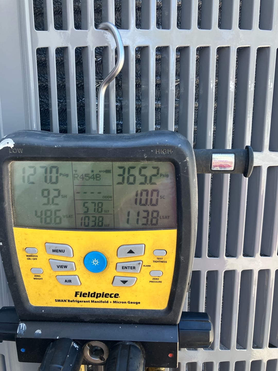 Digital manifold displays operating pressures on a running system with refrigerant, documenting suction and liquid pressures alongside superheat and subcooling.