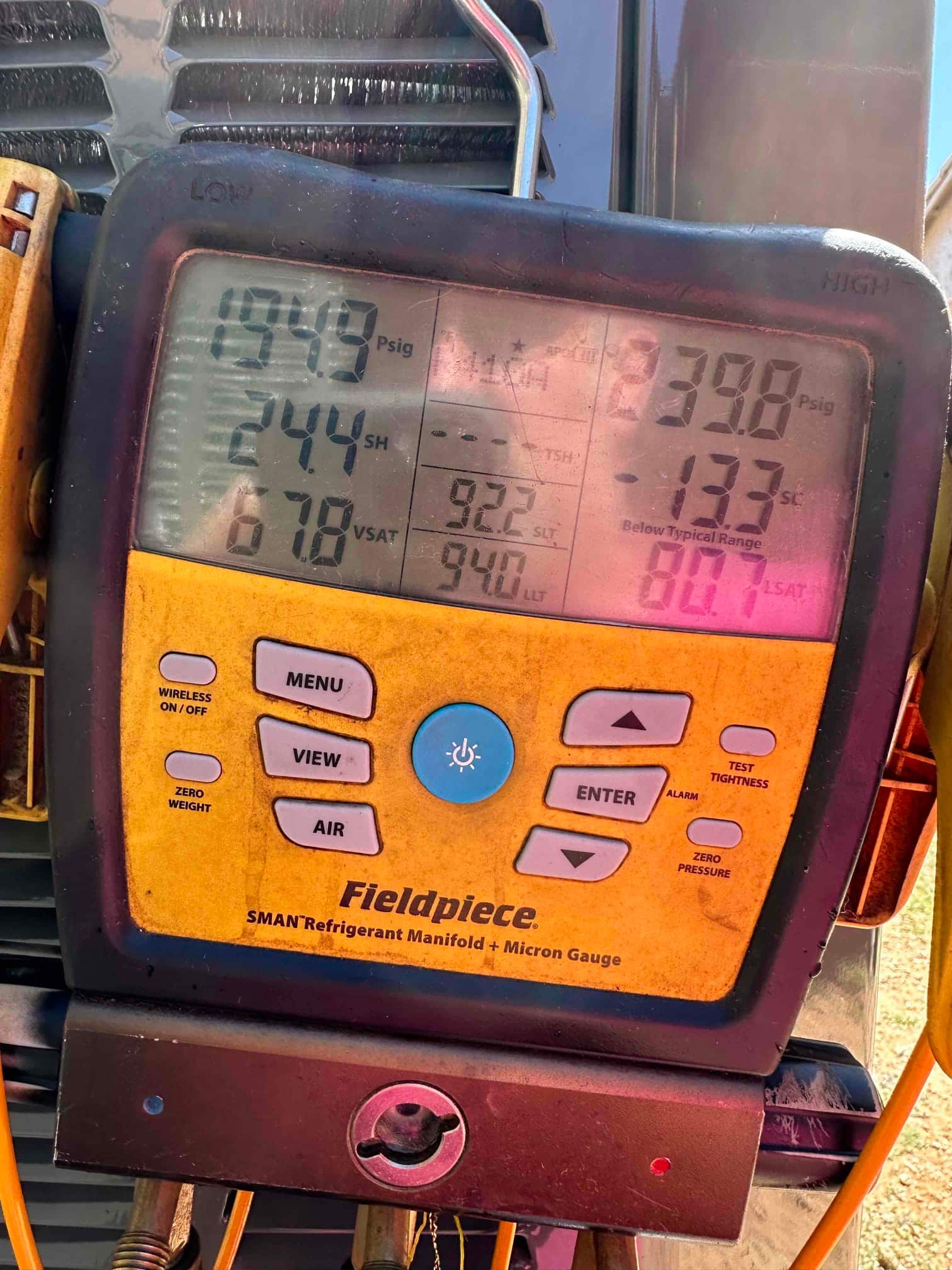 Digital manifold displays operating refrigerant pressures with superheat and subcooling while the air conditioner runs during commissioning.