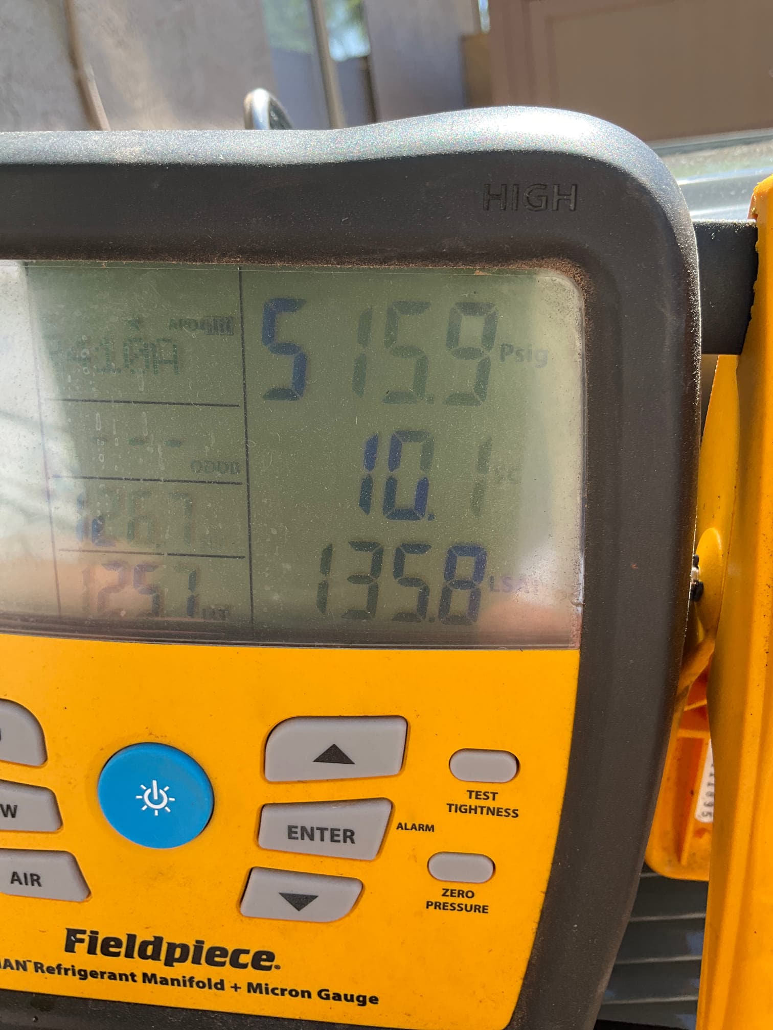 Digital manifold gauge shows system operating with distinct high and low pressures during commissioning on the outdoor unit.