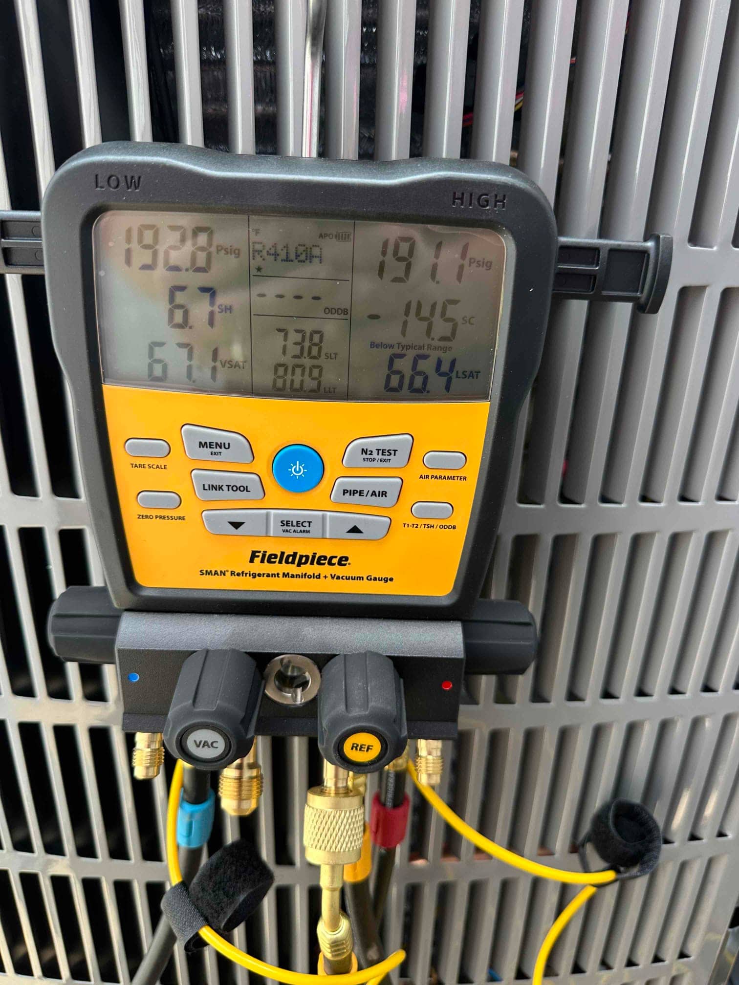 Digital manifold gauges mounted at the outdoor unit show equal pressures on both sides during a nitrogen pressure test.