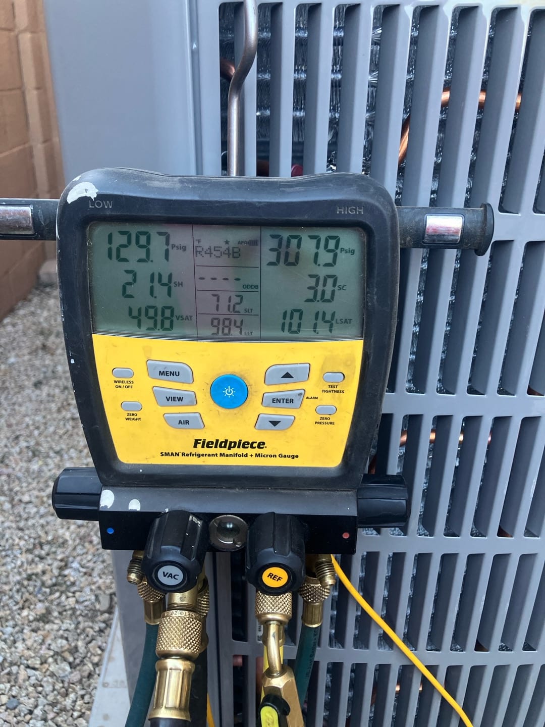 Digital manifold gauges on the outdoor unit show operating pressures while commissioning the system with refrigerant.
