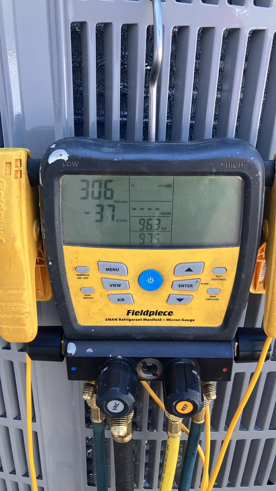 Digital manifold with micron gauge shows 306 microns during system evacuation, indicating a deep vacuum before releasing refrigerant.