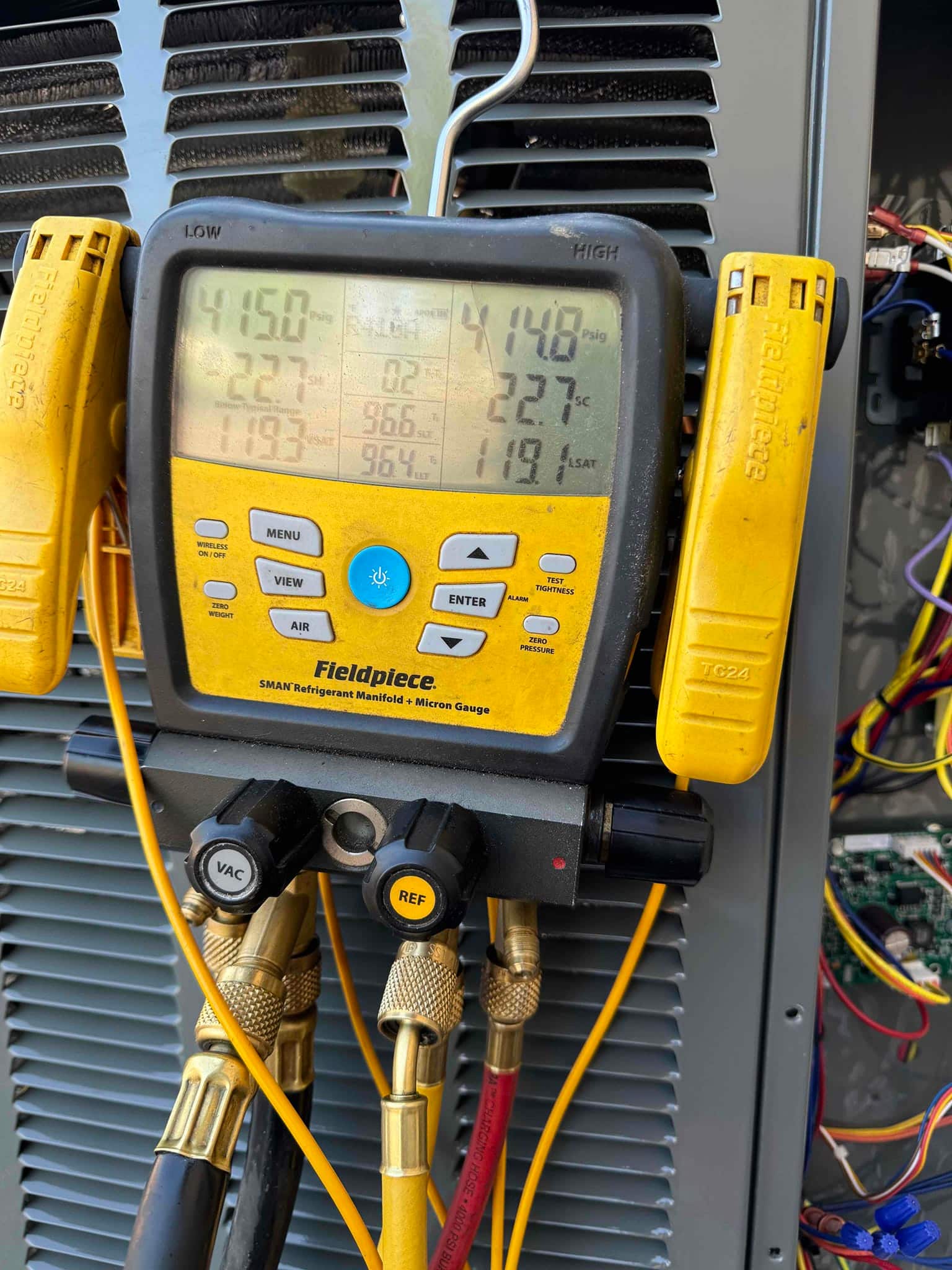 Digital manifold on outdoor unit shows operating pressures with attached temperature clamps during system commissioning.