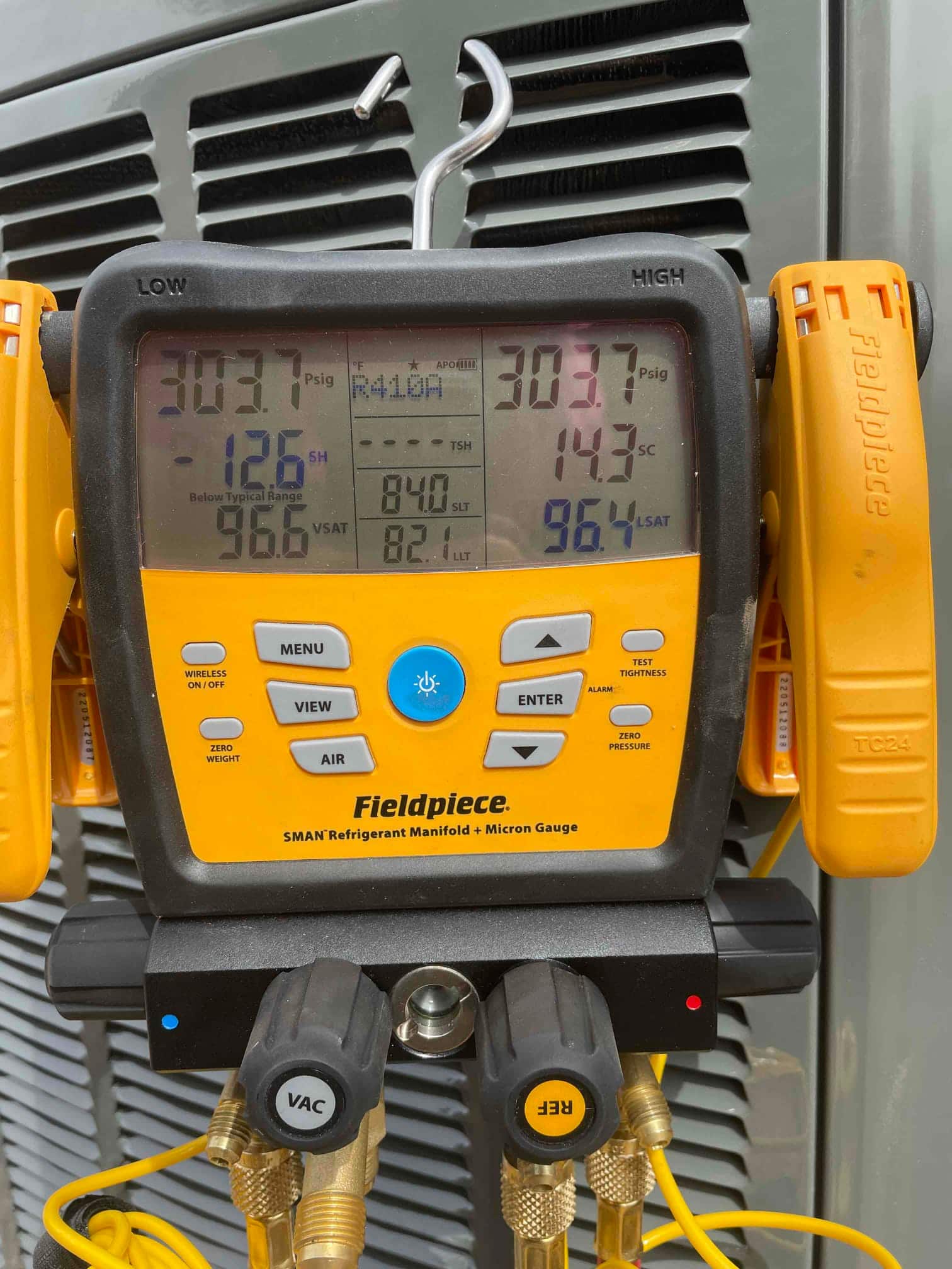 Digital manifold shows both high and low sides at 303 PSI during a nitrogen pressure test on the outdoor condenser.