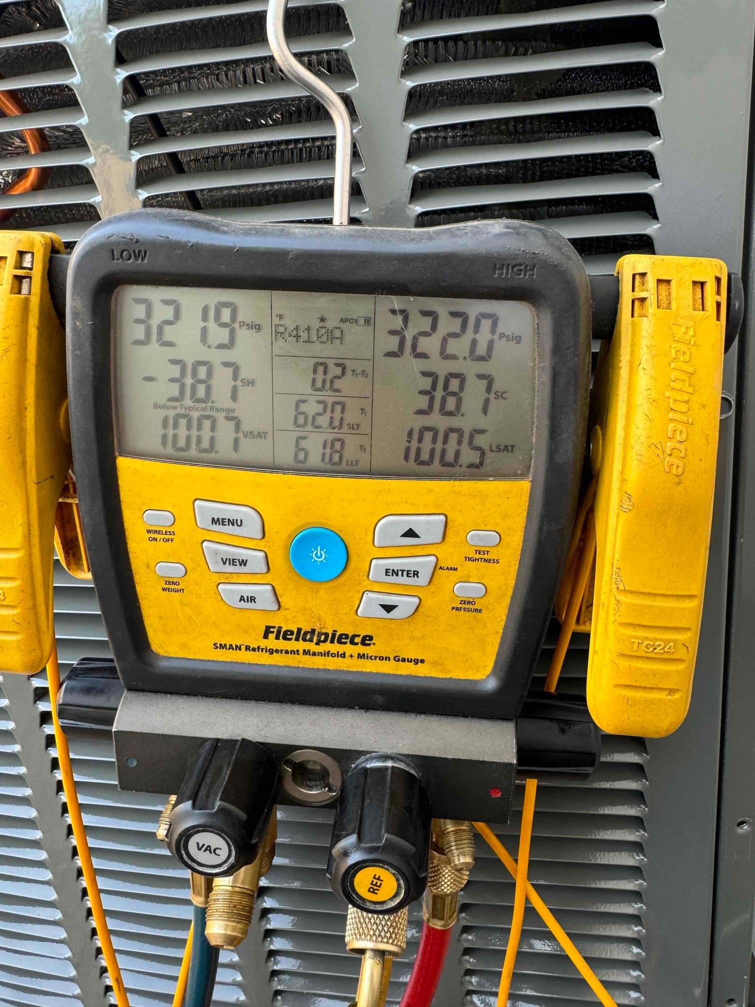 Digital manifold shows both high and low sides holding around 322 PSI during a nitrogen pressure test on the outdoor unit.
