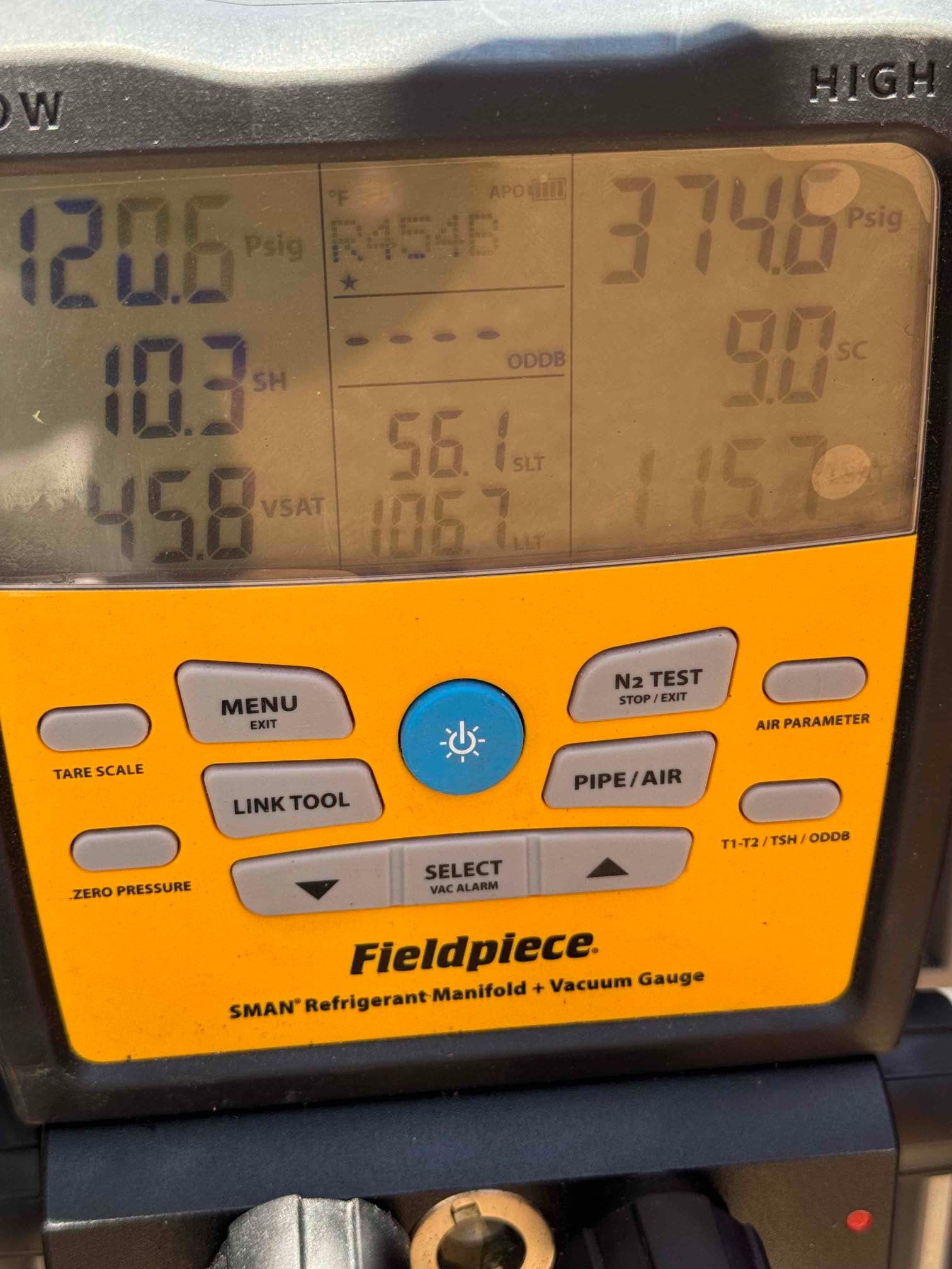 Digital manifold shows operating pressures with R-454B selected: low side 120.6 PSI and high side 374.6 PSI during system commissioning.