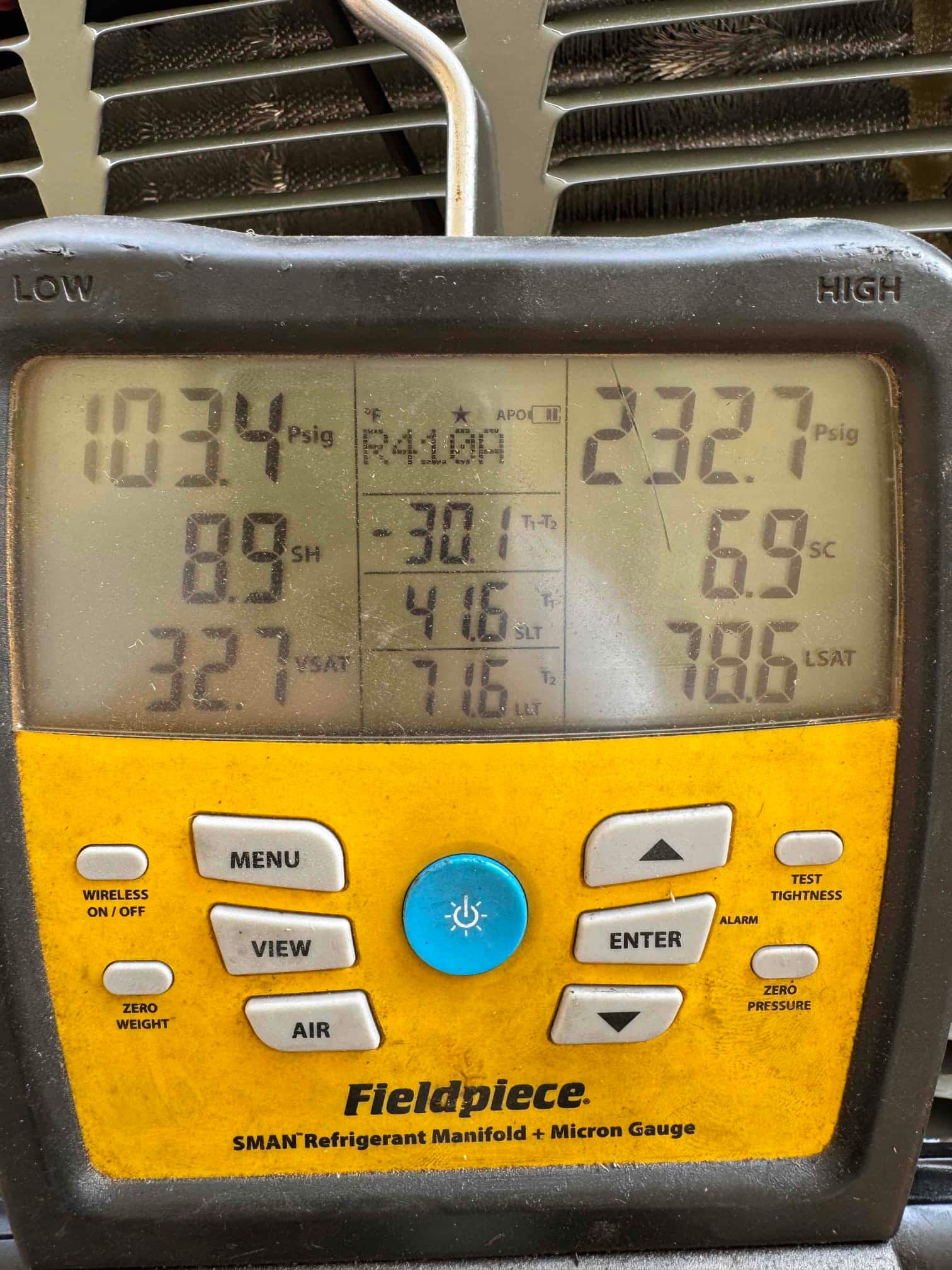 Digital manifold shows operating pressures on an outdoor unit during commissioning, with refrigerant type indicated on the display.