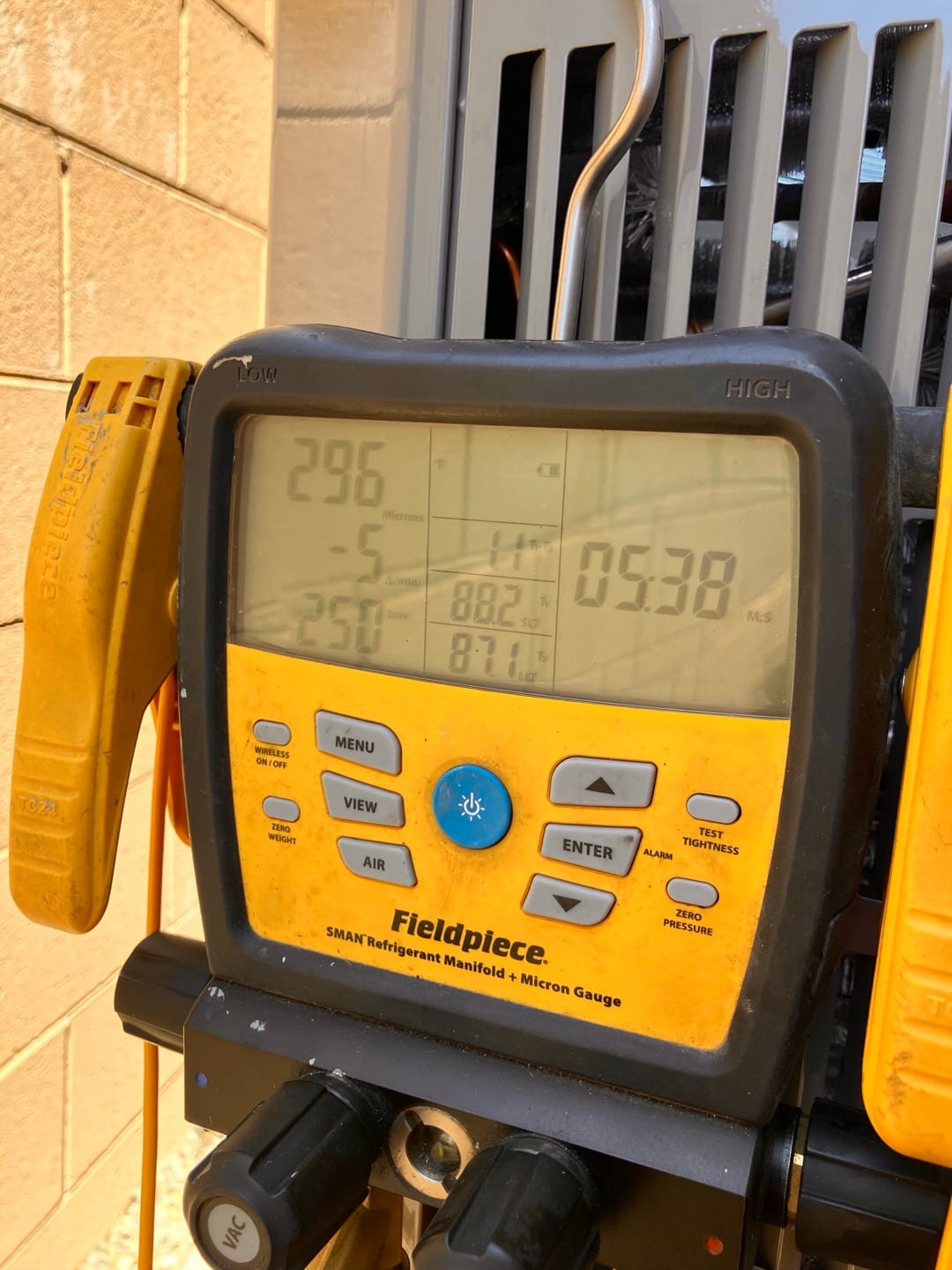 Digital manifold shows operating refrigerant pressures with low side at 296 PSI and high side at 538 PSI during system commissioning.