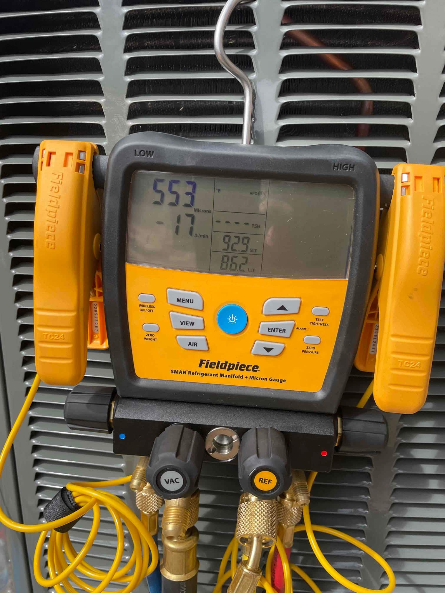 Digital micron gauge on the outdoor unit shows 553 microns during evacuation prior to refrigerant charging.