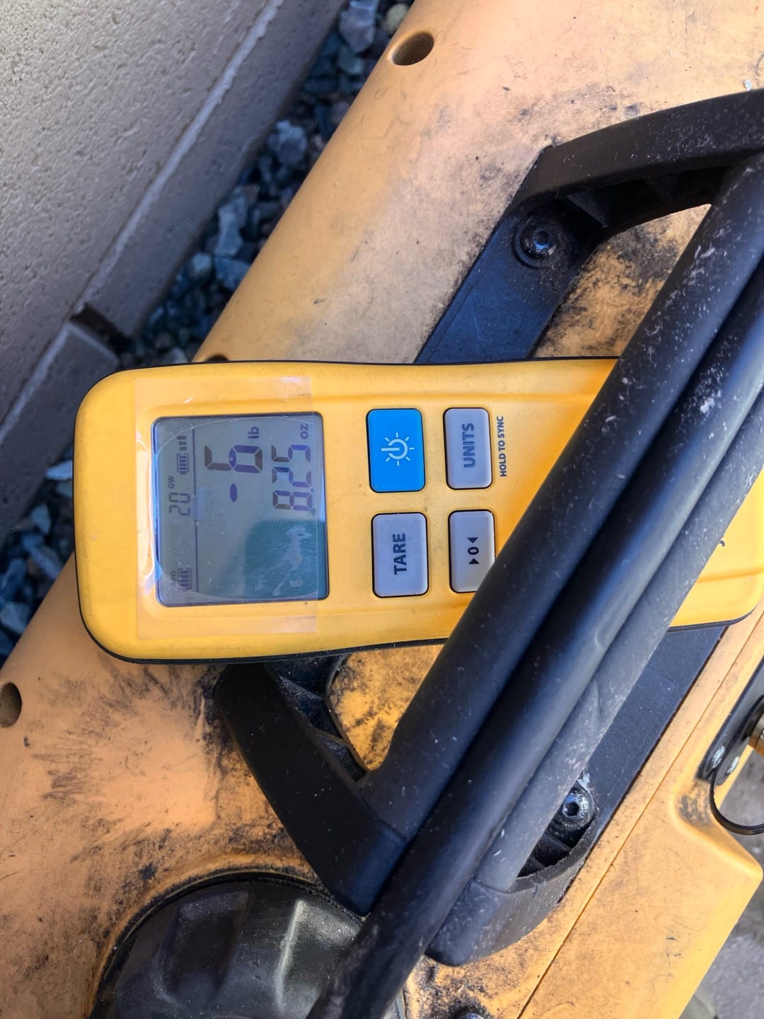 Digital refrigerant scale display shows negative 0.6 pounds and 8.5 ounces during charging work at the outdoor unit.
