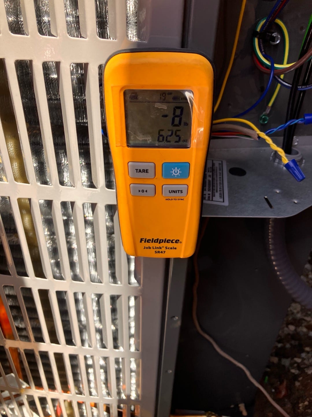 Digital refrigerant scale displays 8 lb 6.25 oz during charging at the outdoor condenser service area.