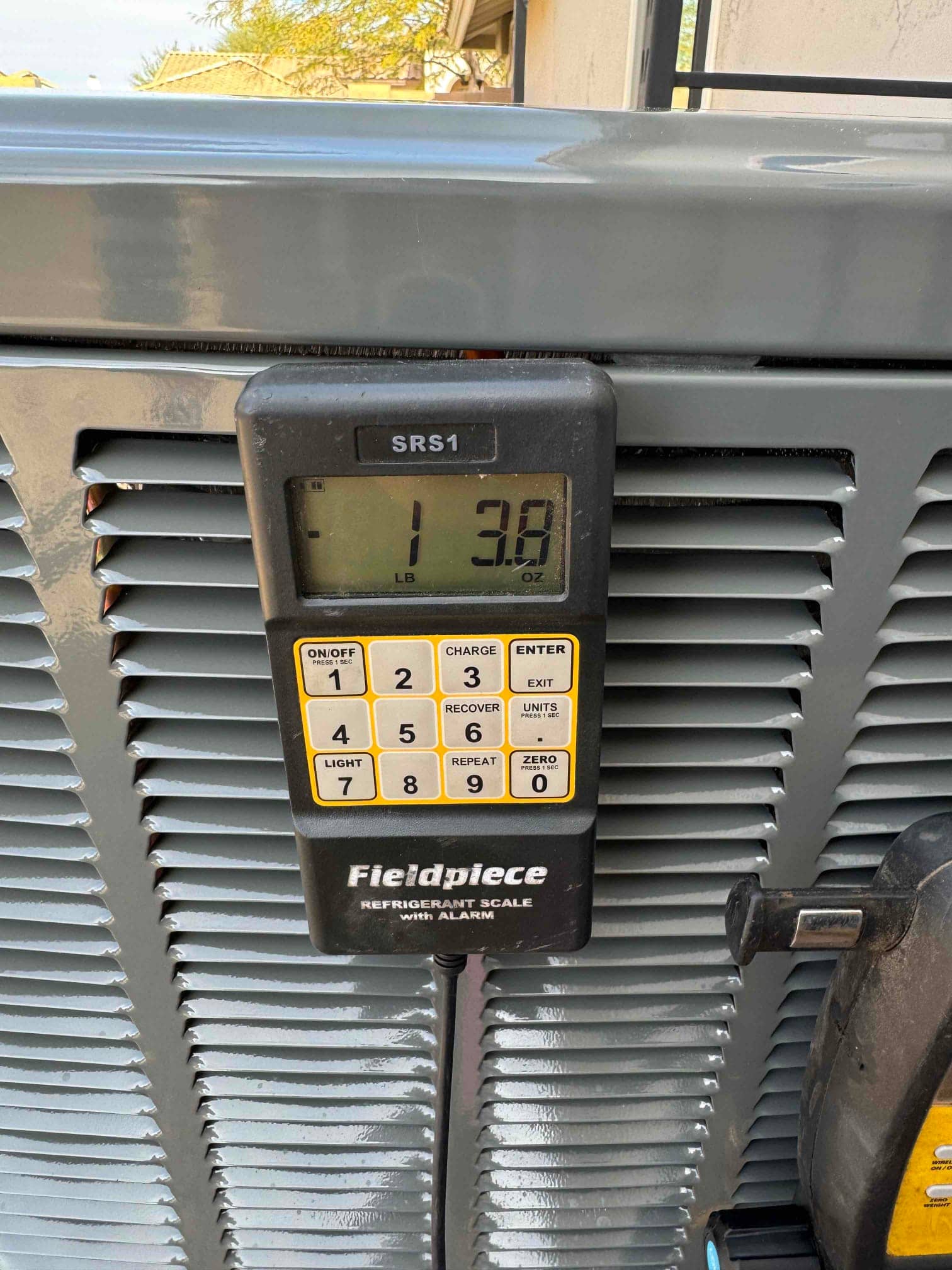 Digital refrigerant scale displays 1 pound 3.8 ounces during charging at the outdoor condenser.