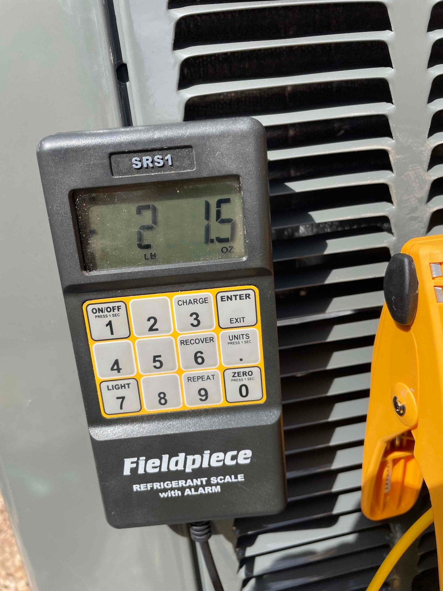 Digital refrigerant scale at the outdoor unit displays 2 lb 1.5 oz during charging of the new air conditioning system.