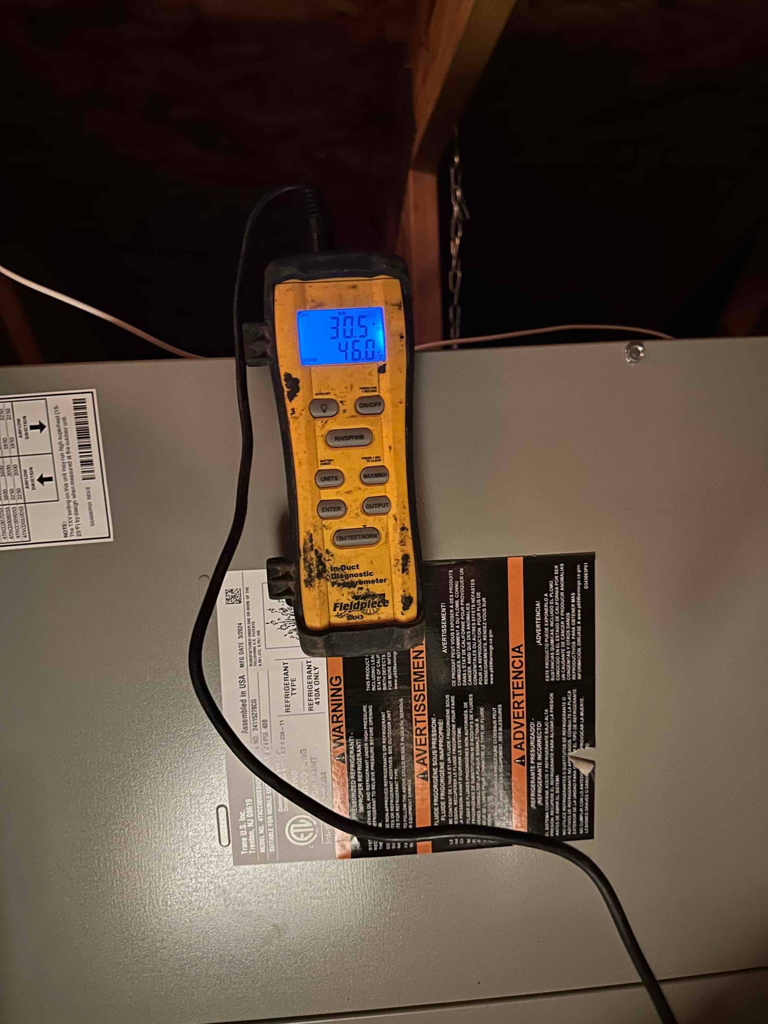 Digital thermometer on the air handler shows 30.5°F and 46.0°F while documenting air-side temperature readings during commissioning.