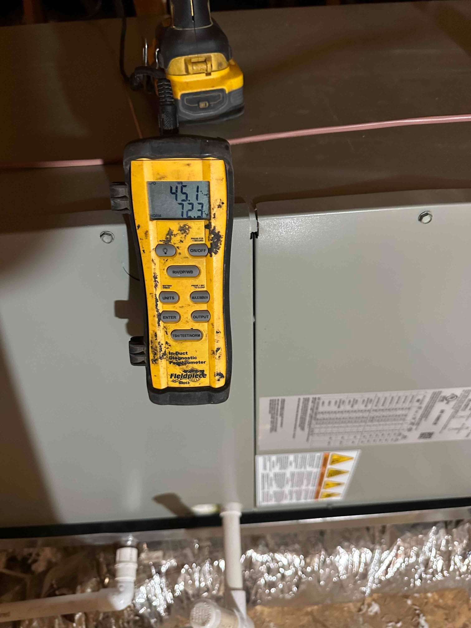Digital thermometer on the air handler shows supply air at 45.1°F and return air at 72.3°F during cooling verification.