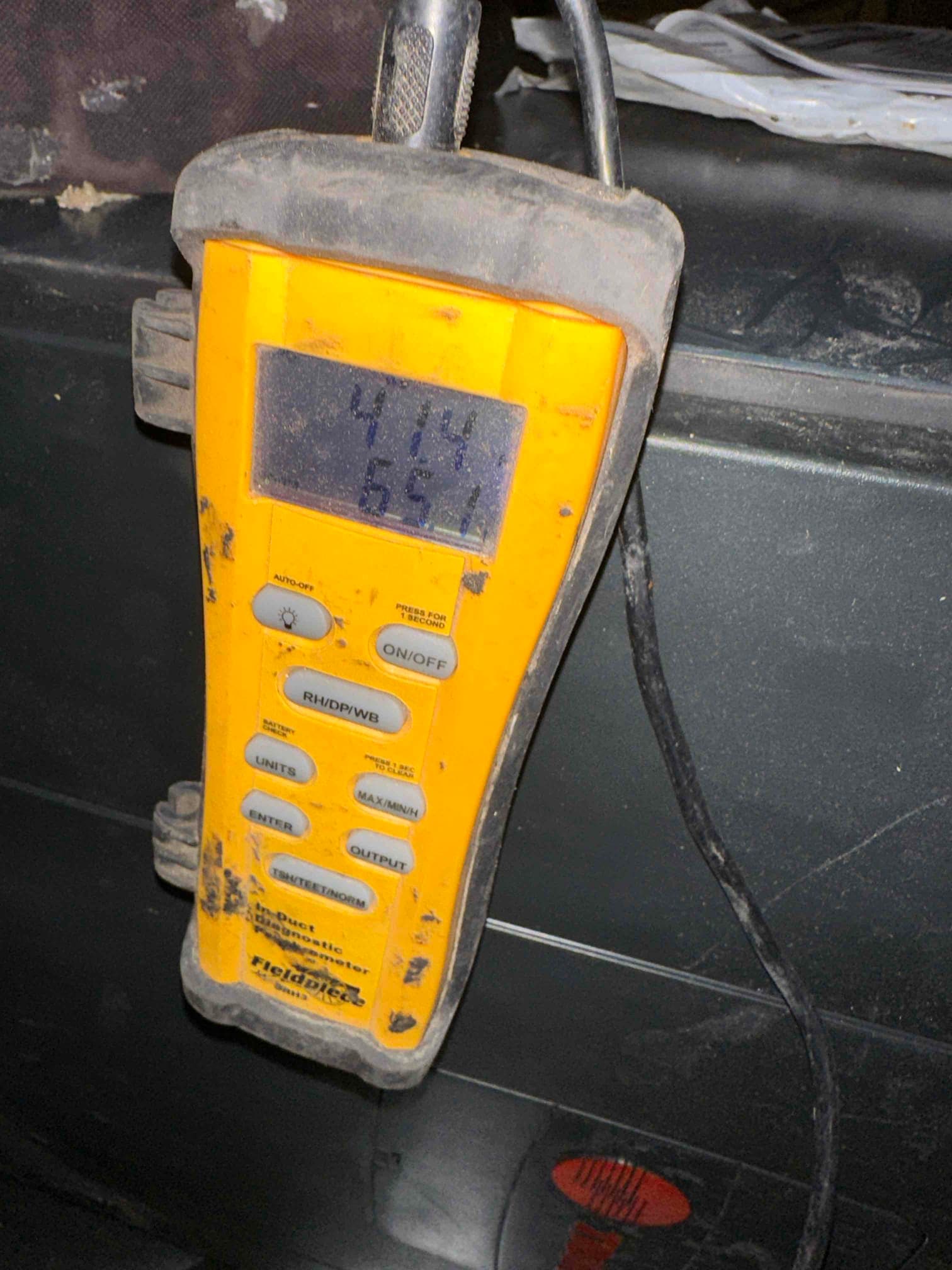 Digital thermometer displays 41.4 and 65.1 degrees while checking air temperatures during system startup.