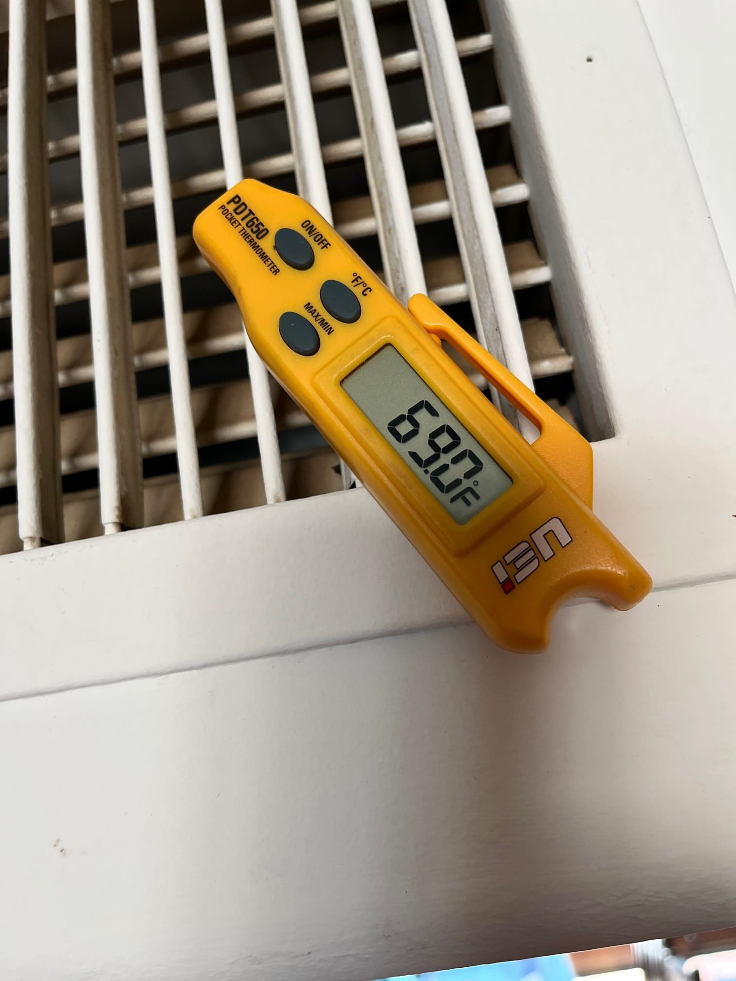 Digital thermometer placed at a grille shows 69.0°F during air-side commissioning of the HVAC system.