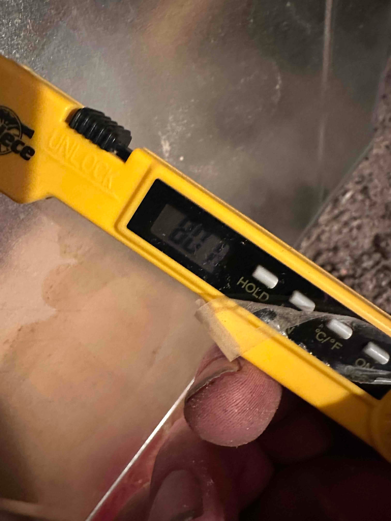 Digital thermometer probe inserted into sheet metal duct, documenting air temperature during system commissioning.