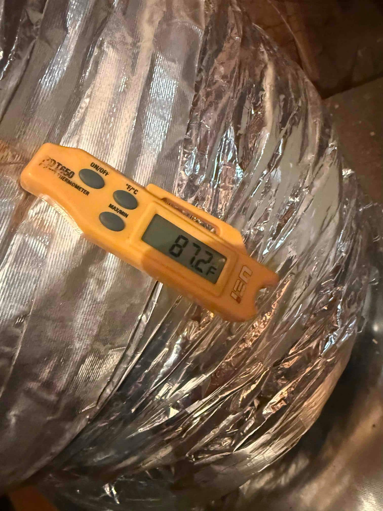Digital thermometer reads 87.2°F at a flexible duct during return air temperature check.