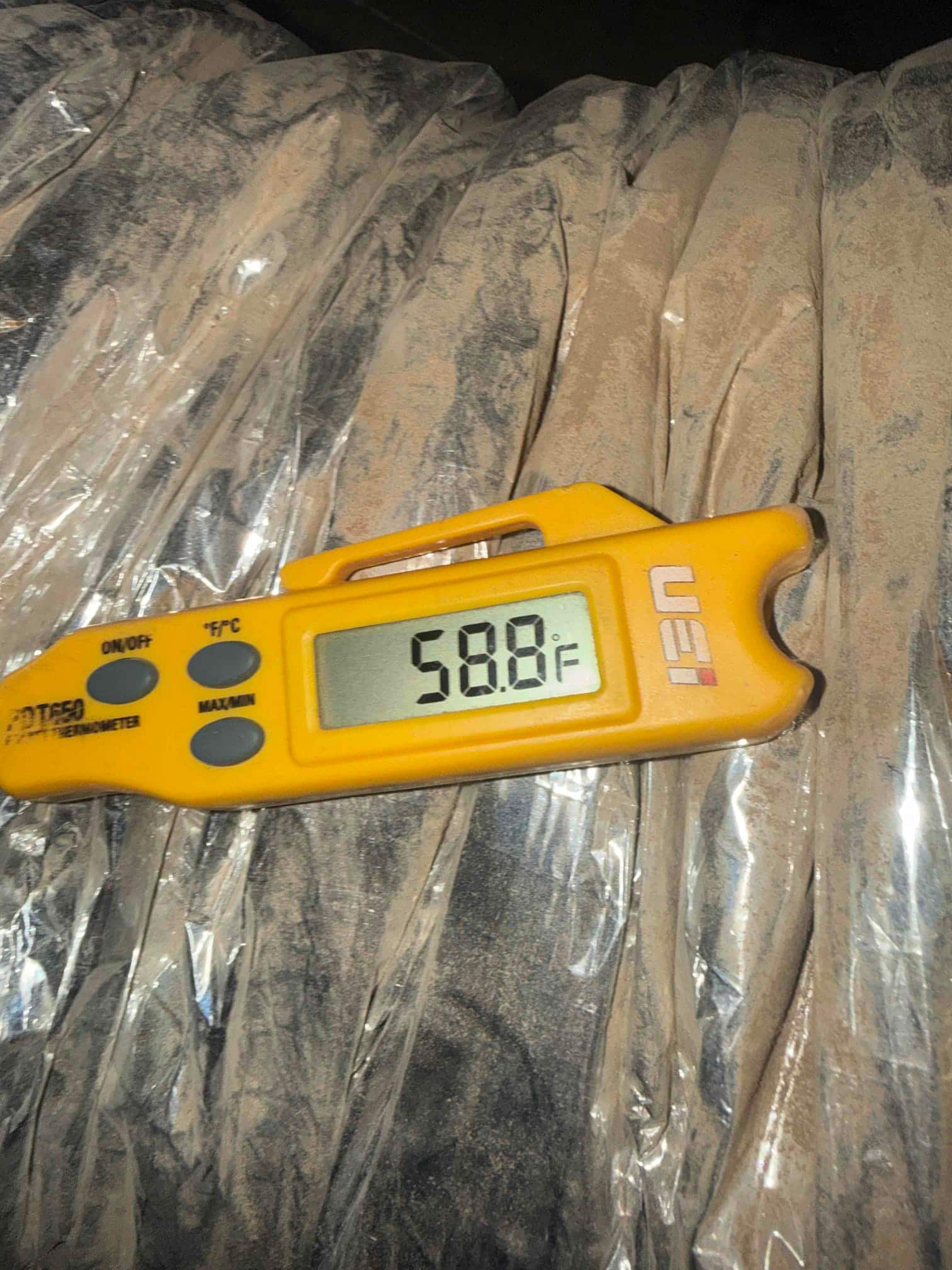 Digital thermometer shows 58.8°F while measuring cooled air at the supply side of the system.