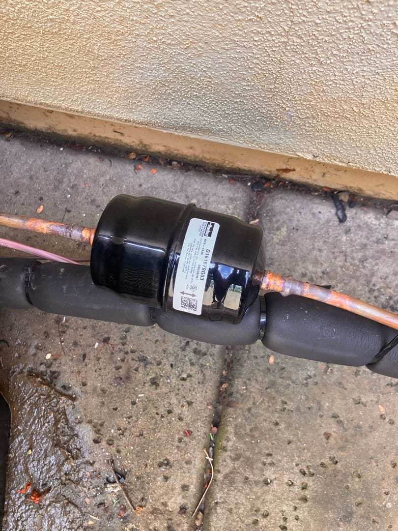 Inline refrigerant filter-drier brazed into the copper line set with insulation around the adjacent tubing.