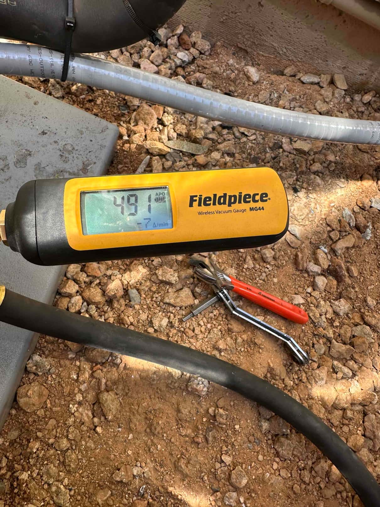 Micron gauge connected during evacuation shows 491 microns, confirming a deep vacuum before charging the system.
