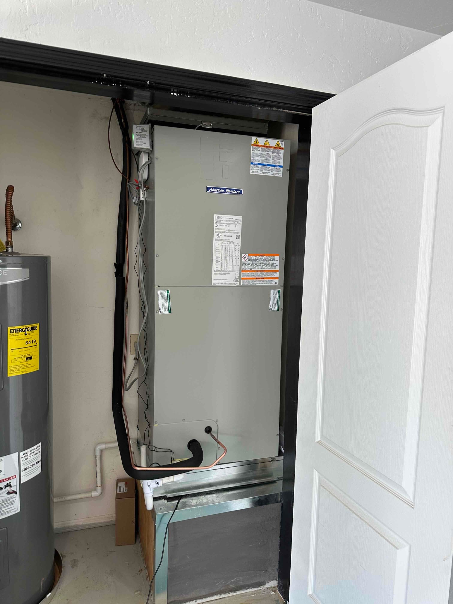 New air handler installed in closet with insulated refrigerant lines, condensate drain, and return plenum connection visible.