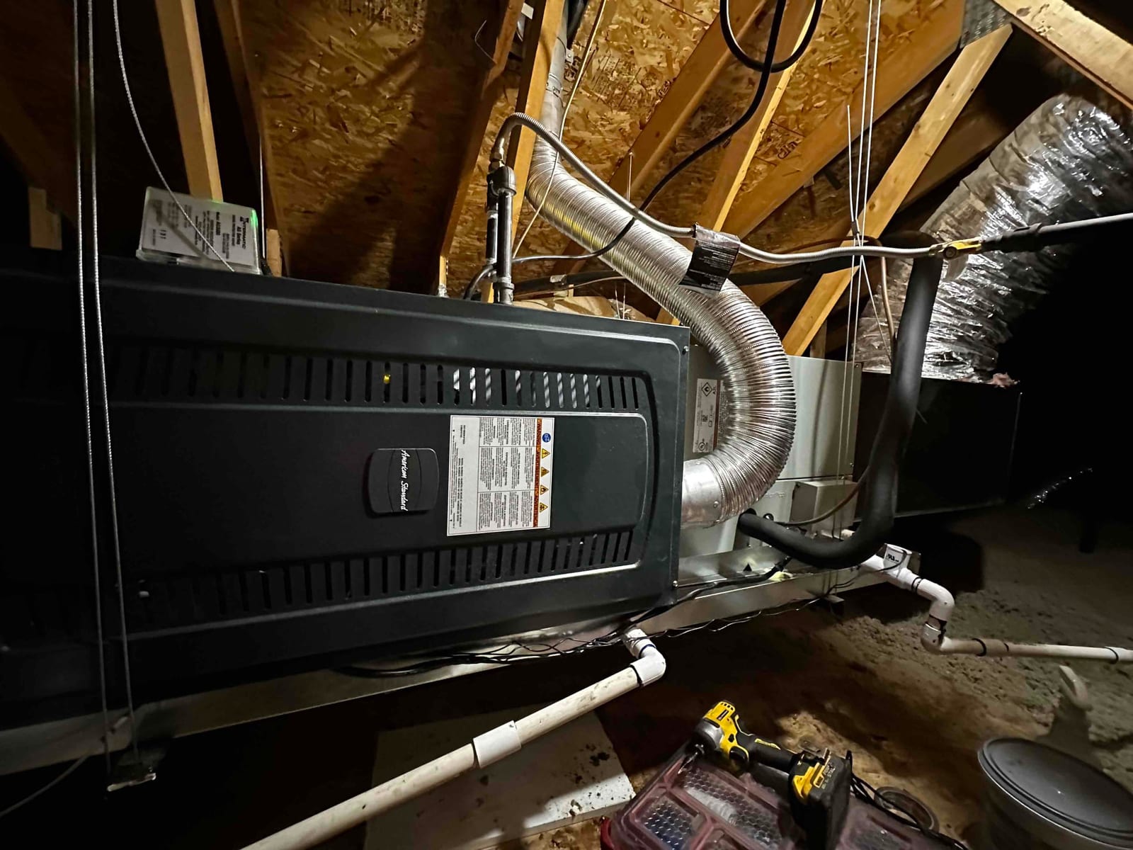 New attic air handler installed on a suspended platform with insulated refrigerant lines, flex duct connections, and a plumbed condensate drain.